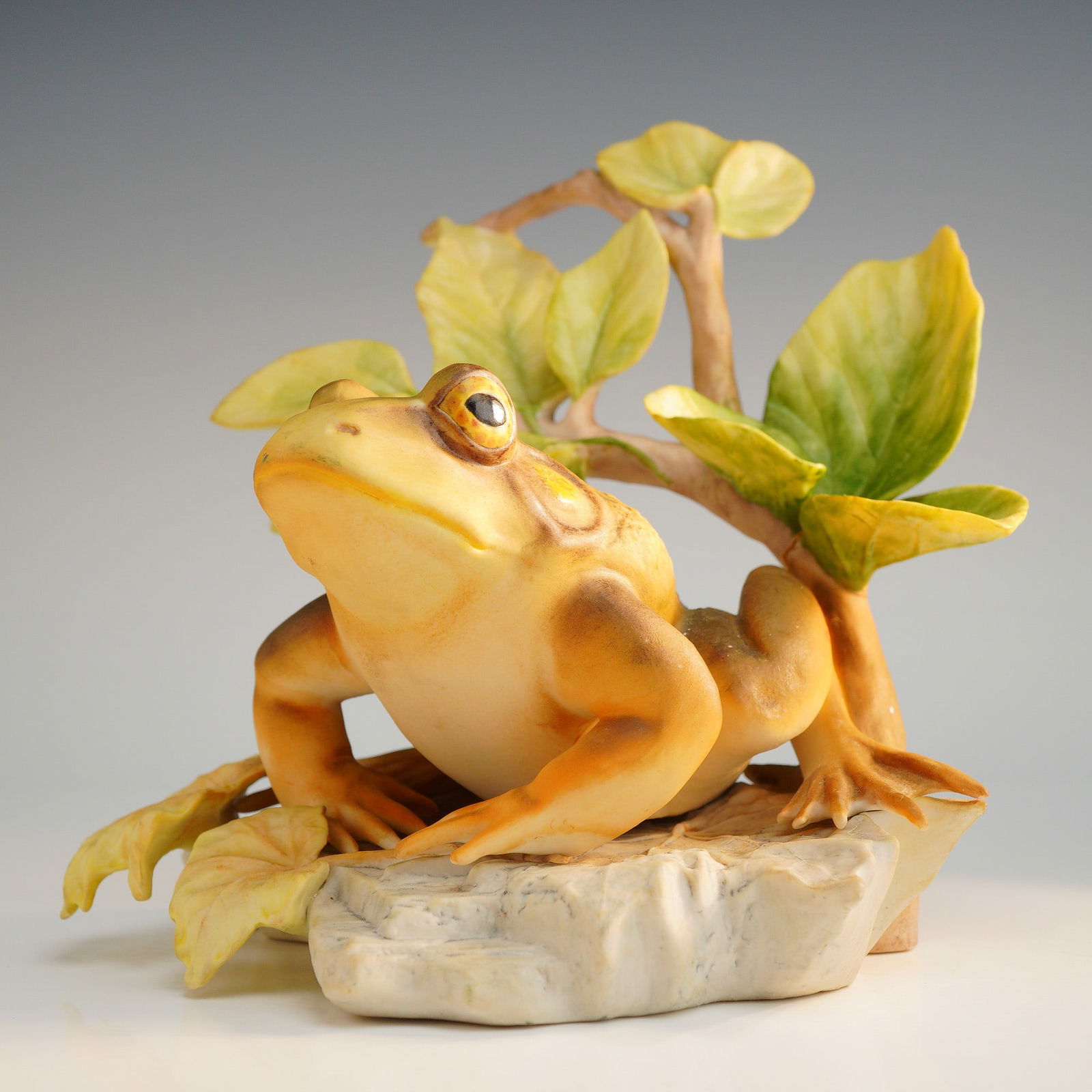 Cybis Porcelain Figurine, American Bullfrog Enchanted Prince: A Cybis bisque porcelain figurine titled American Bullfrog Enchanted Prince. The piece features a naturalistically modeled frog situated on a textured, rock-like base. The frog is decorated in shades