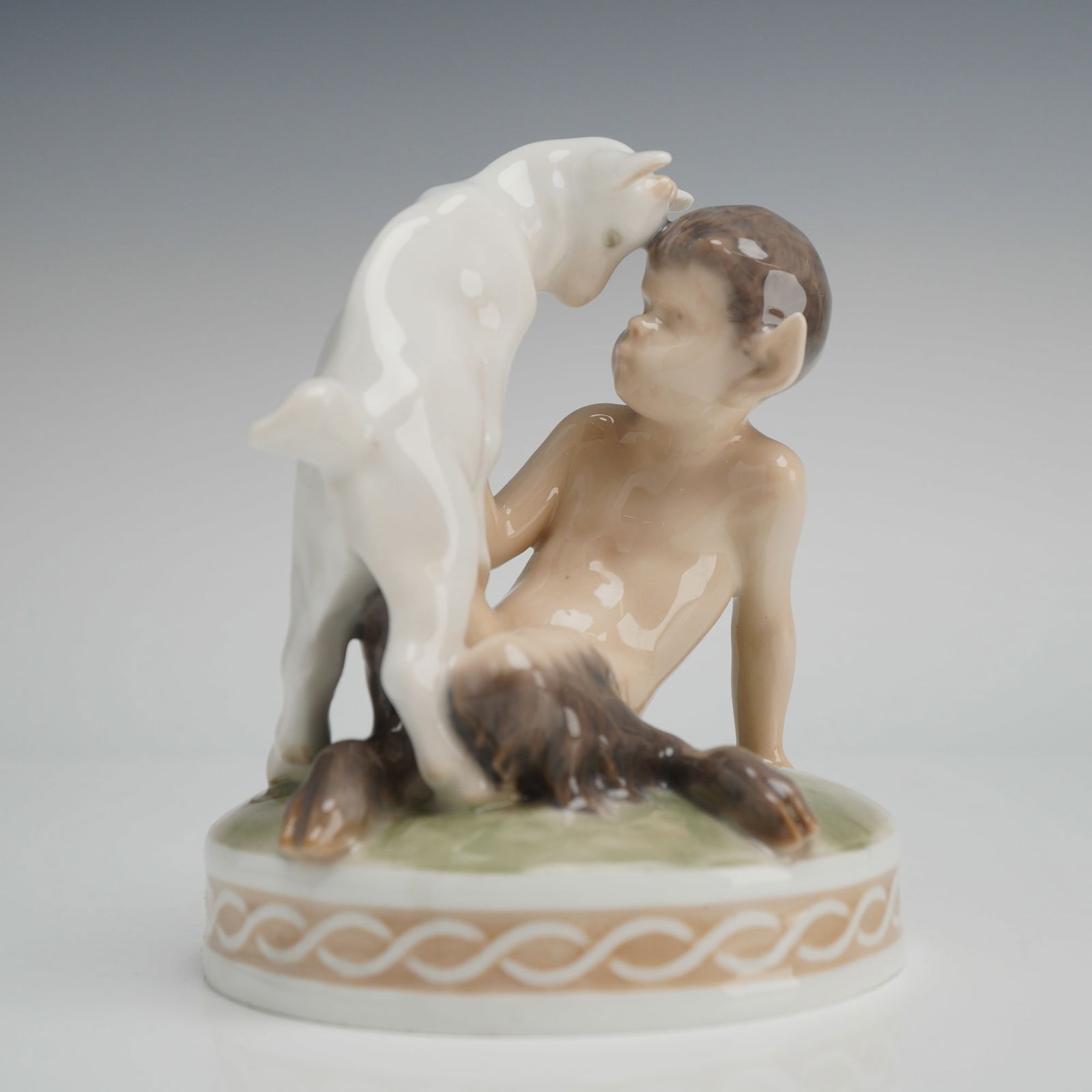 Royal Copenhagen Porcelain Figurine, Faun with Goat: This Royal Copenhagen porcelain figurine, titled Faun with Goat, is model number 498 and was designed by artist Christian Thomsen. The figure depicts a seated faun with pointed ears and human features