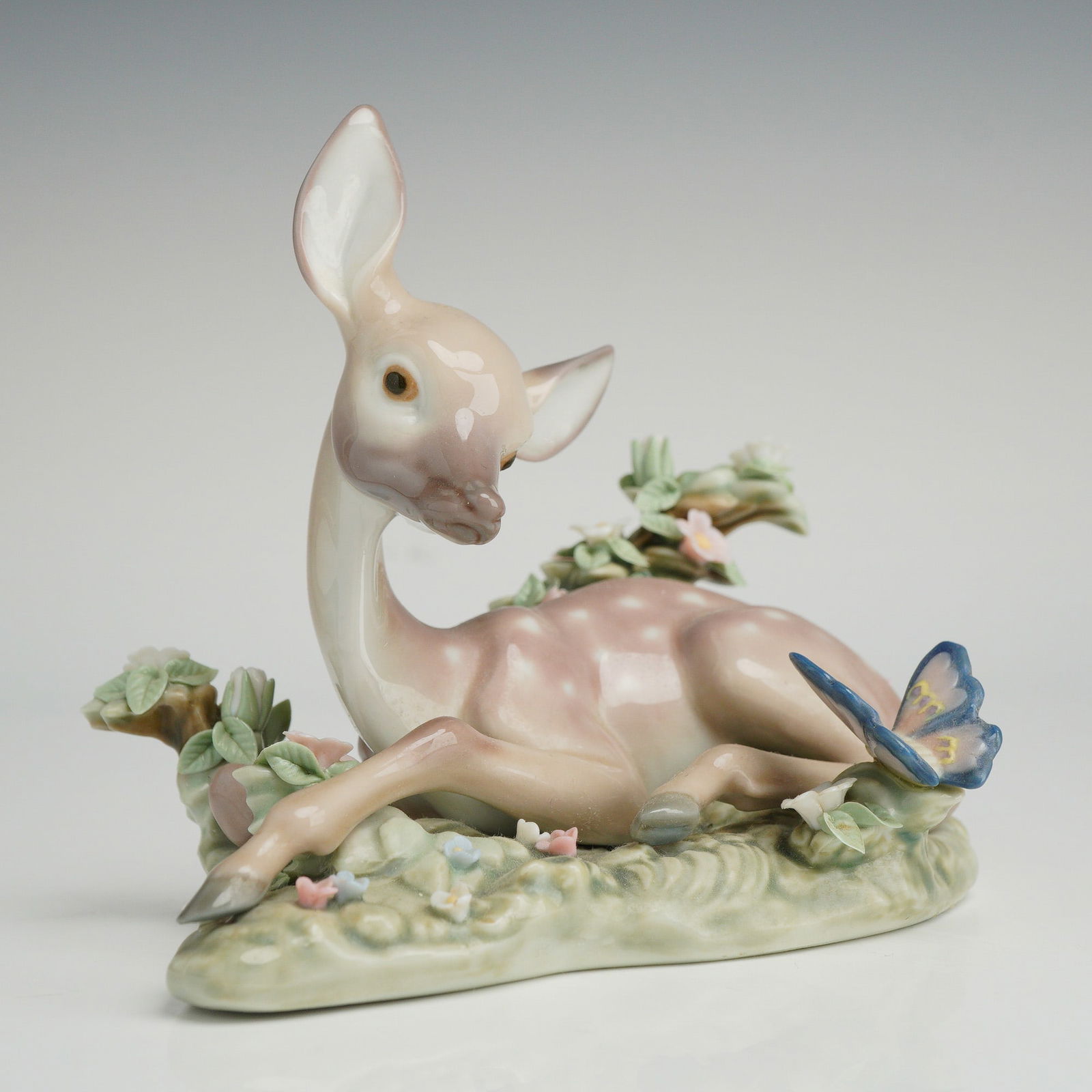 Lladro A Quiet Moment Porcelain Figurine 1005673: Lladro A Quiet Moment glazed porcelain figurine, model number 1005673. The piece depicts a seated fawn in a landscape setting with a blue butterfly perched on nearby flower. The figurine is finished i