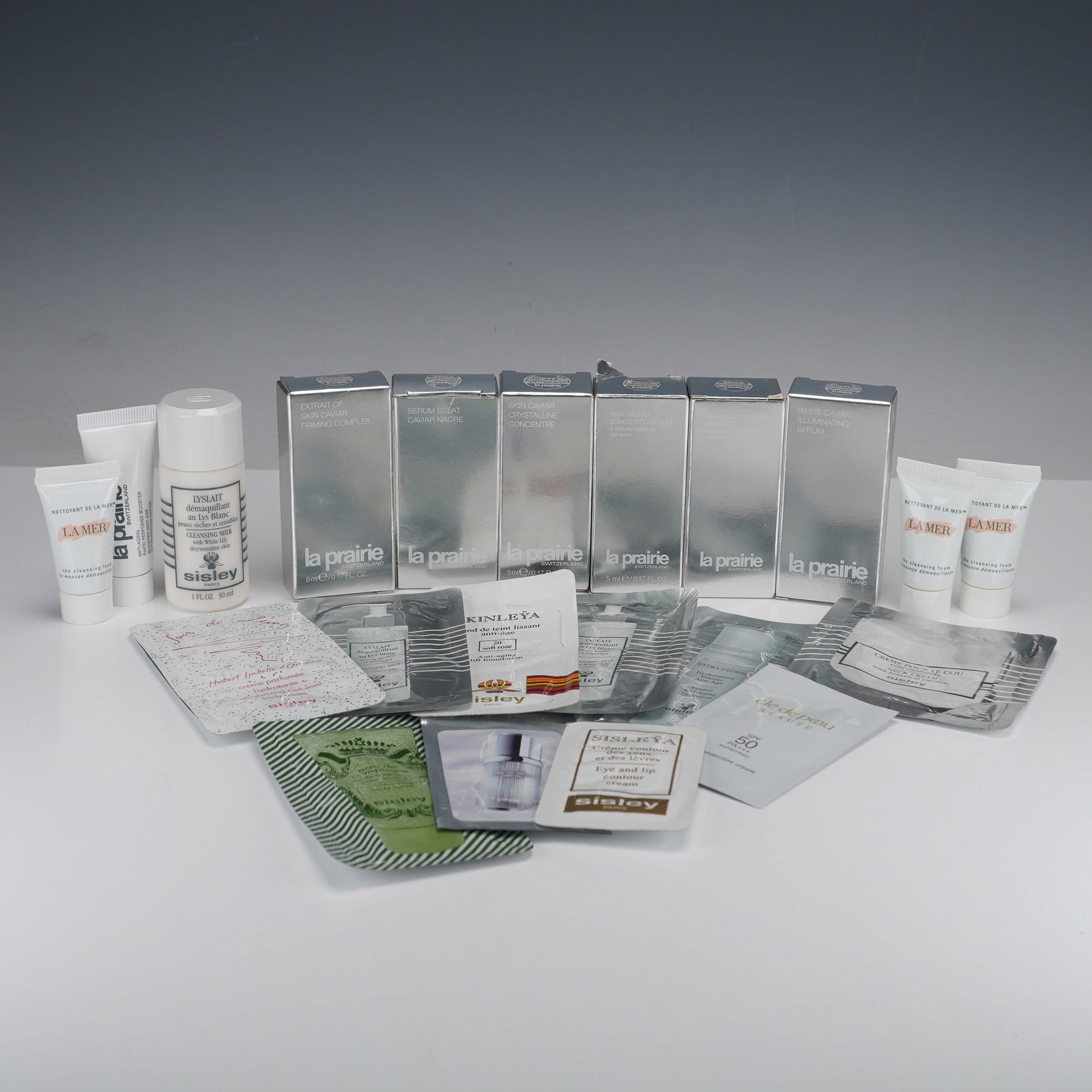 A Collection of La Prairie Skin Caviar, Sisley, and La Mer Luxury Skincare: A collection of luxury cosmetic and skincare products, predominantly in sample or travel sizes, featuring prominent brands including La Prairie, Sisley, and La Mer. The assortment includes items from