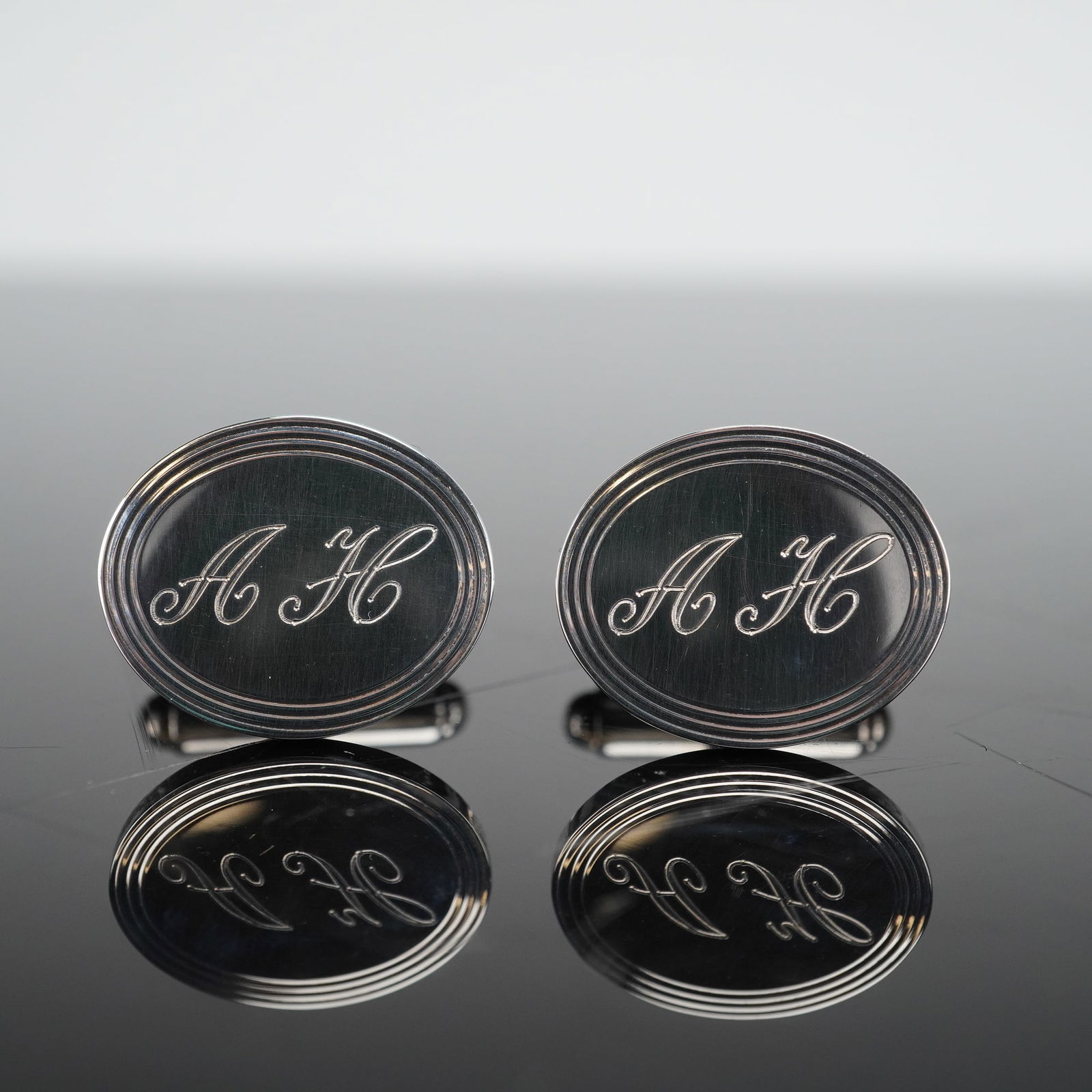 Tiffany & Co. Sterling Silver Engine-Turned Oval Cufflinks: A pair of Tiffany & Co. sterling silver oval cufflinks, featuring a polished oval face distinguished by concentric lines forming a border around a central field. The central field of each cufflink is