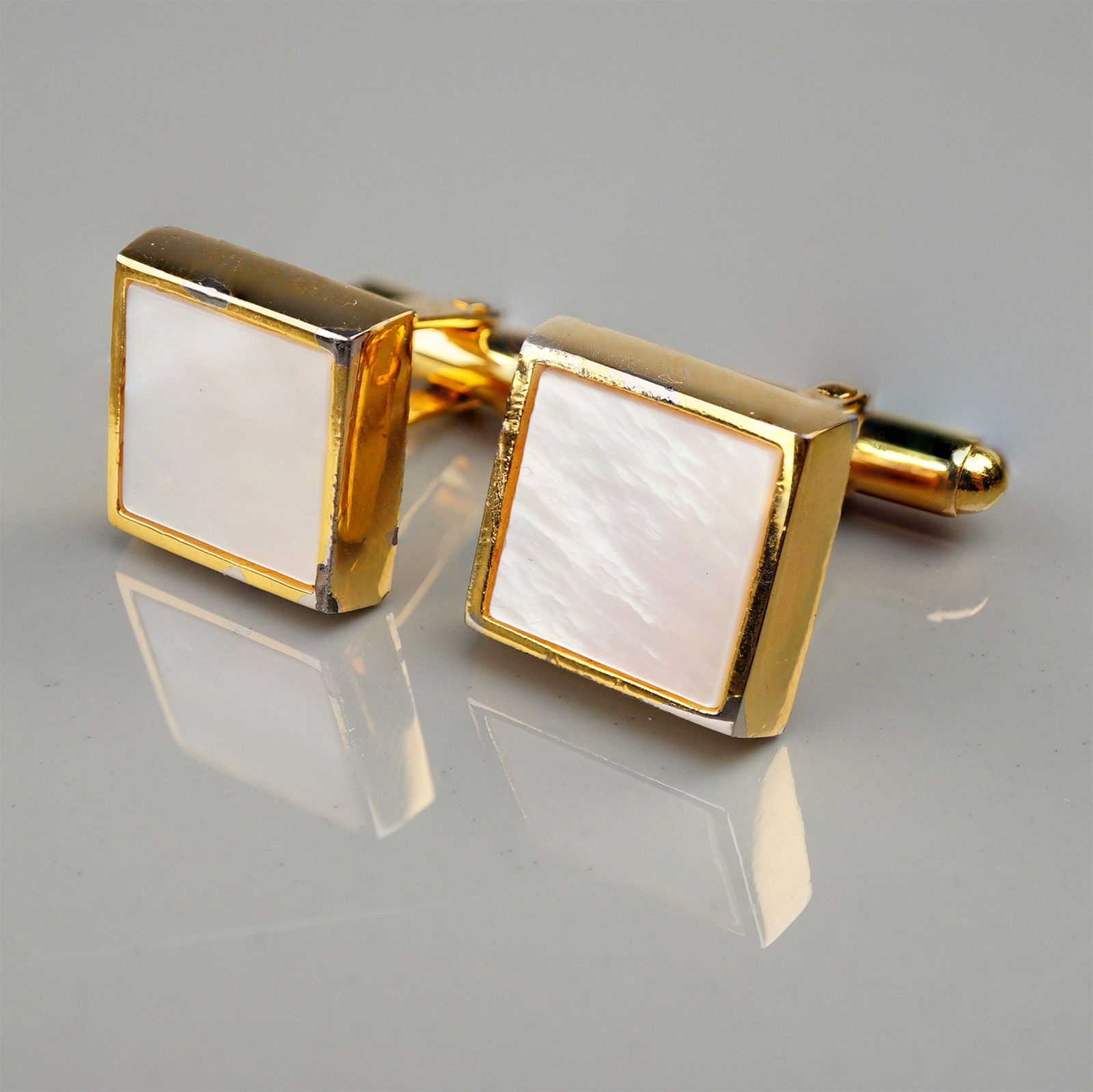 A Pair of Vintage Christian Dior Square Mother-of-Pearl Cufflinks: A pair of vintage Christian Dior cuff links, featuring square faces set with highly iridescent white mother-of-pearl (MOP) inlay. The cufflinks are constructed of gold-toned metal and utilize a bullet