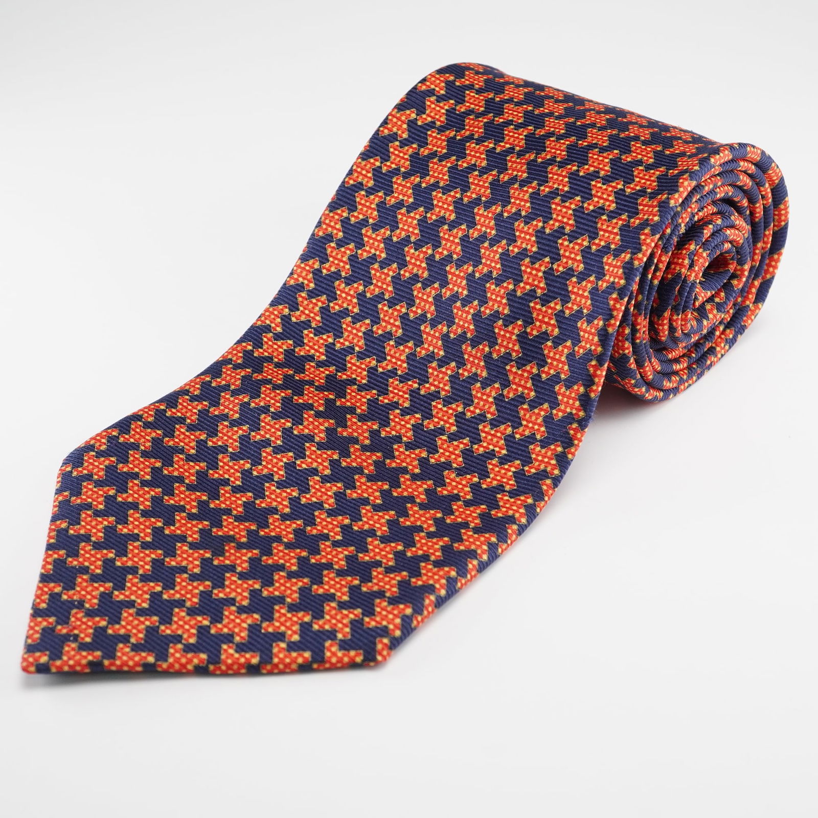A Stefano Ricci Navy Blue and Orange-Red Geometric Pure Silk Necktie: A Stefano Ricci pure silk necktie. Crafted from pure silk, this modern mens necktie features a tessellating geometric pattern of orange-red, four-lobed shapes accented with small yellow dots, set agai