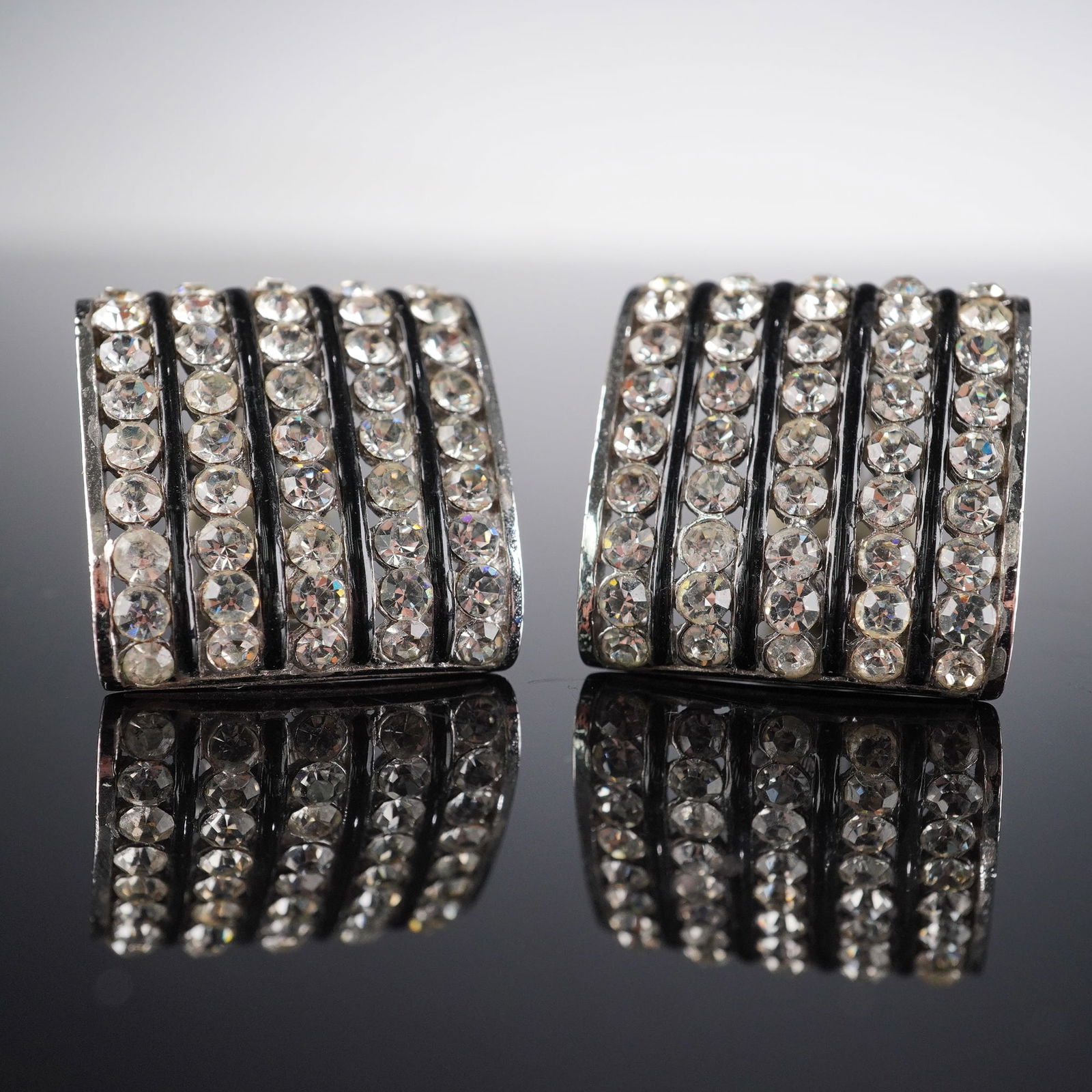A Pair of CINER Five-Row Rhinestone Clip-On Earrings: A matching pair of broadly rectangular clip-on earrings, each adorned with five vertical rows of individually set, clear faceted rhinestones within a silver-tone metal frame. The reverse of each earri