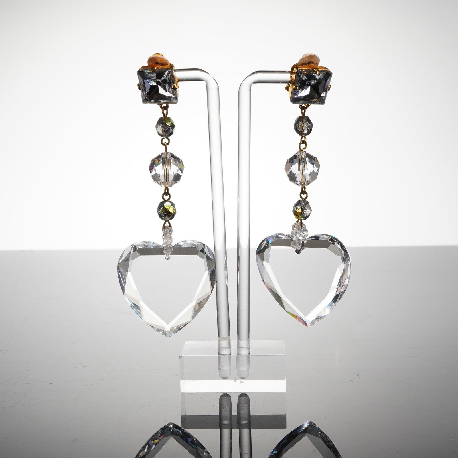 Pair of Yves Saint Laurent Hearts and Beads Clip-On Earrings: A pair of costume jewelry clip-on earrings with a long, dangling form constructed from gold-toned metal and features faceted components. The top element is a square faceted stone set into the clip-on