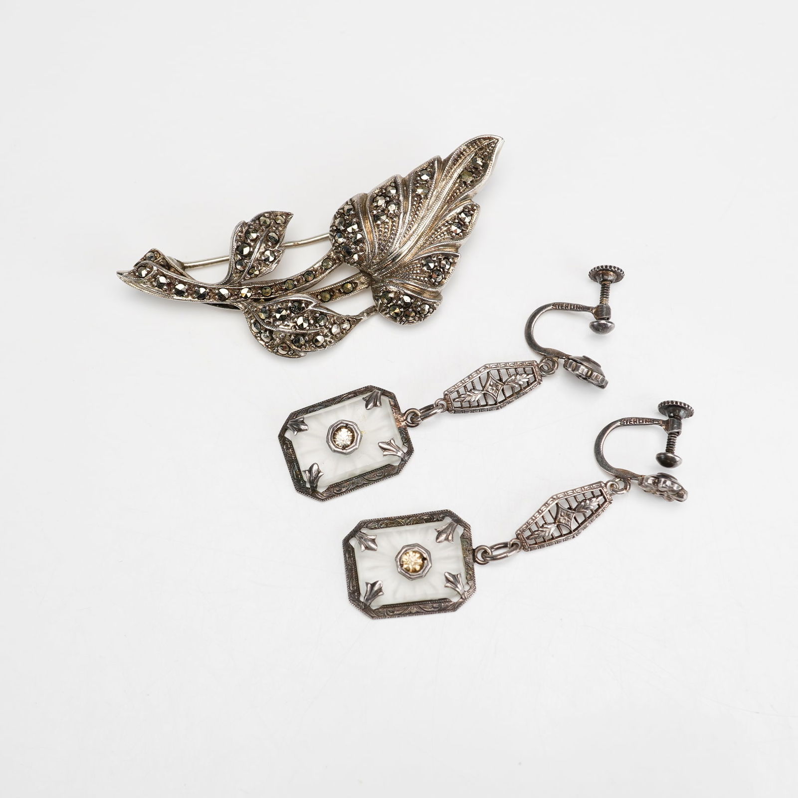 2pc Sterling Silver and Argentina 935 Earrings and Brooch: This three-piece jewelry set consists of a foliate-motif brooch and a pair of Art Deco-style dangle earrings. The brooch is crafted from Argentina 935 silver, marked 935 and ARGENTINA with a maker's m