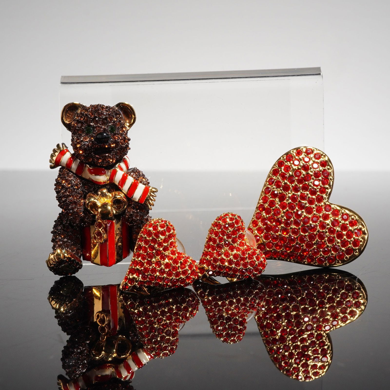 Collection of Four St John Gold Tone Jewelry Pieces: A collection of four pieces of costume jewelry attributed to St. John, consisting of two brooches and one pair of clip-back earrings. The items are crafted from gold-tone base metal and decorated