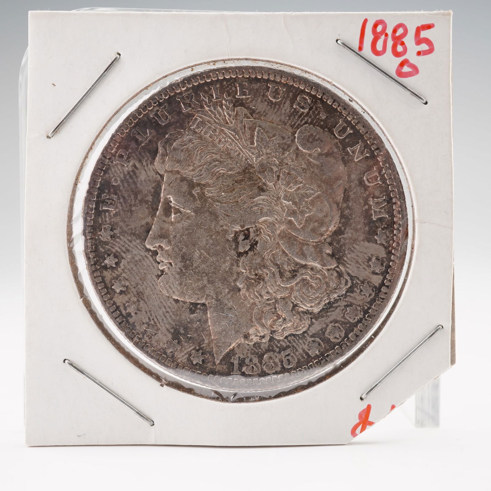 1885-O Morgan Silver Dollar: United States Morgan Silver Dollar, 1885-O, struck at the New Orleans Mint. Designed by George T. Morgan, the obverse features a left-facing profile of Liberty wearing a Phrygian cap adorned with
