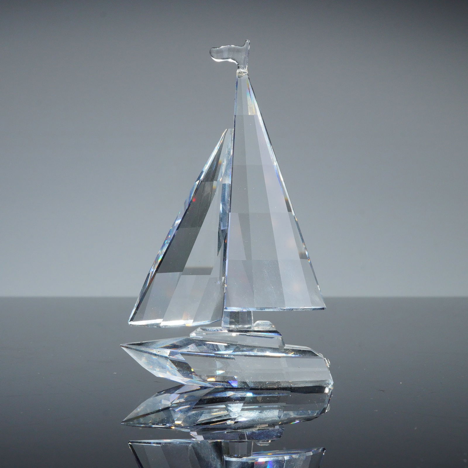Swarovski Crystal Figurine, Sailboat: A Swarovski faceted lead crystal figurine of a sailboat, model number 183269. The piece is constructed from clear crystal with geometric facets on the hull and sails, topped with a small flag on the m
