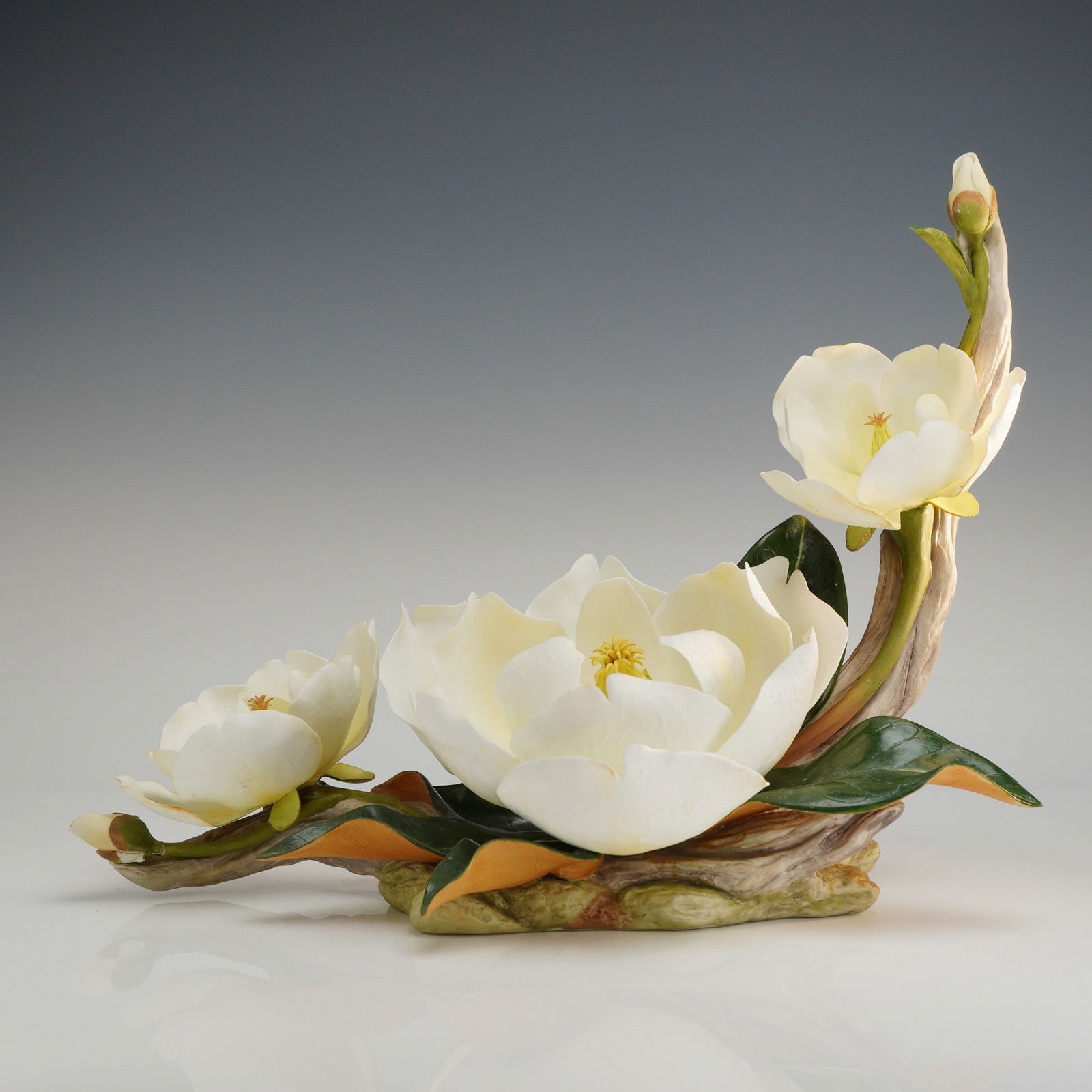 Boehm Porcelain Limited Edition Figurine, Magnolia Grandiflora No 22: A Boehm porcelain Magnolia Grandiflora flower figurine produced in 1986. This hand-painted bisque porcelain sculpture features three cream-colored blossoms in varying stages of bloom alongside two clo