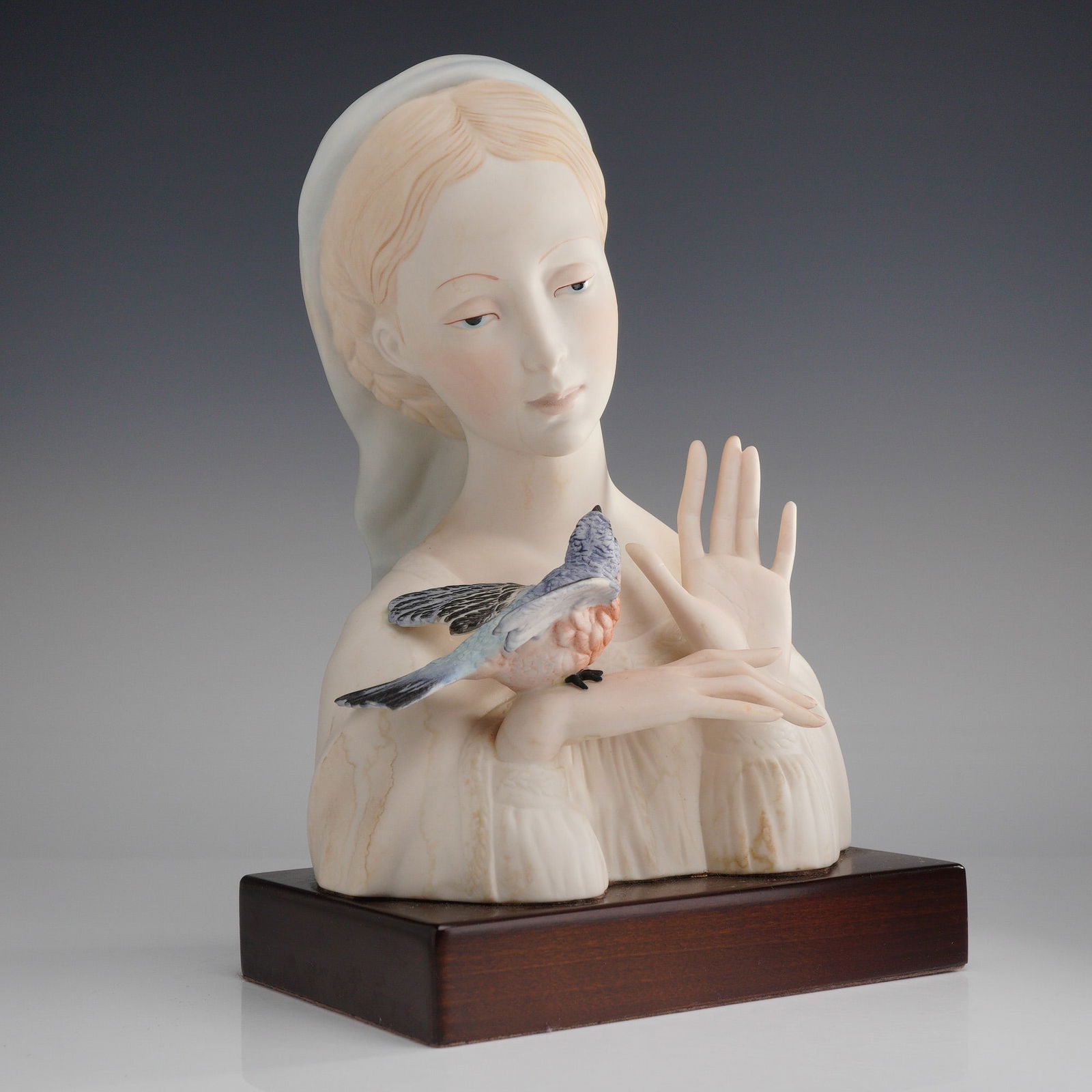 Cybis Porcelain Bust, Madonna with Bird: A Cybis bisque porcelain bust from the Biblical Collection. The sculpture is executed in matte finish porcelain with hand-painted details. The figure is depicted with a white head covering and a small