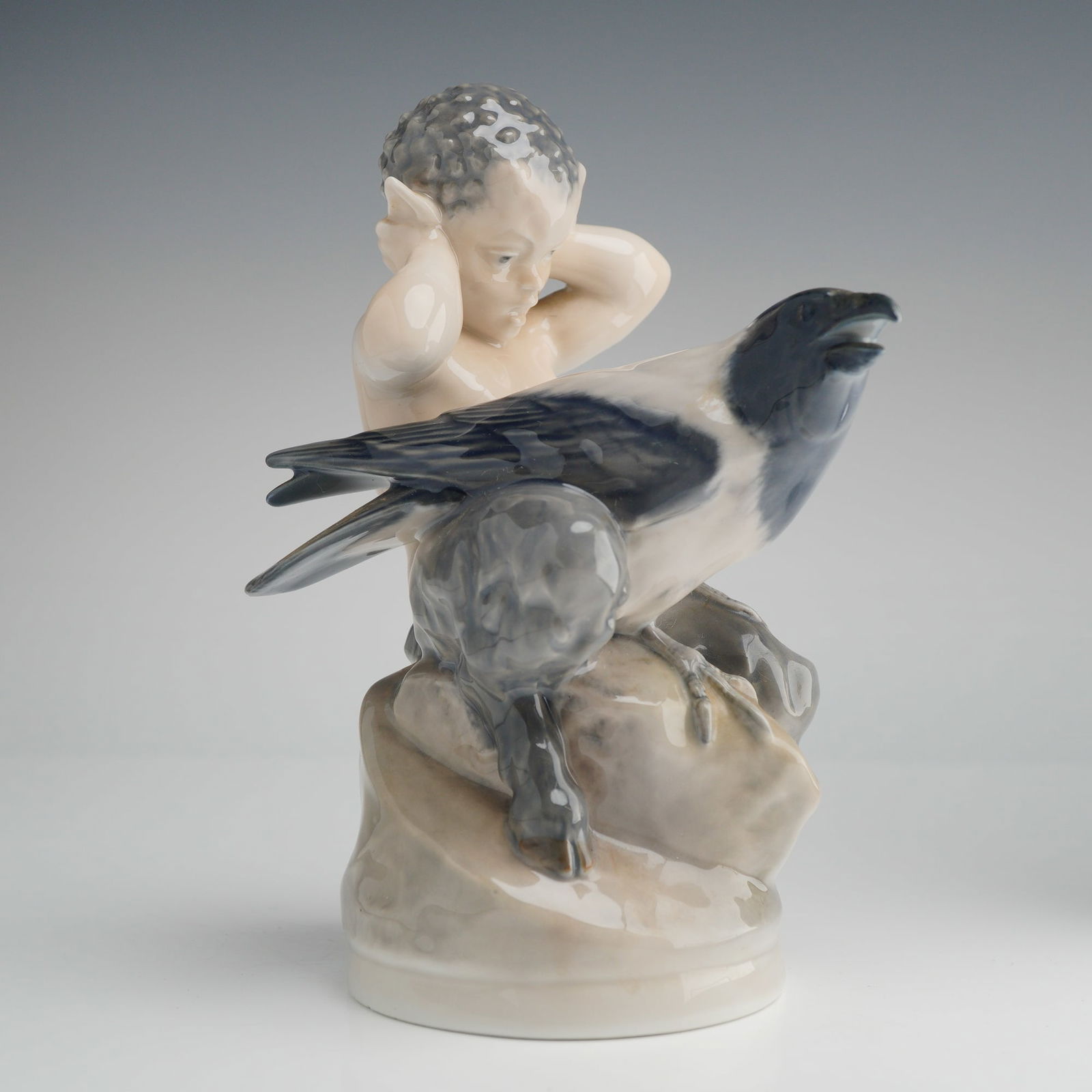 Royal Copenhagen Porcelain Figurine, Faun with Crow: A Royal Copenhagen porcelain figurine titled Faun with Crow, model number 2113, designed by Christian Thomsen. The piece depicts a young faun or satyr seated upon a rocky base, covering his ears as a