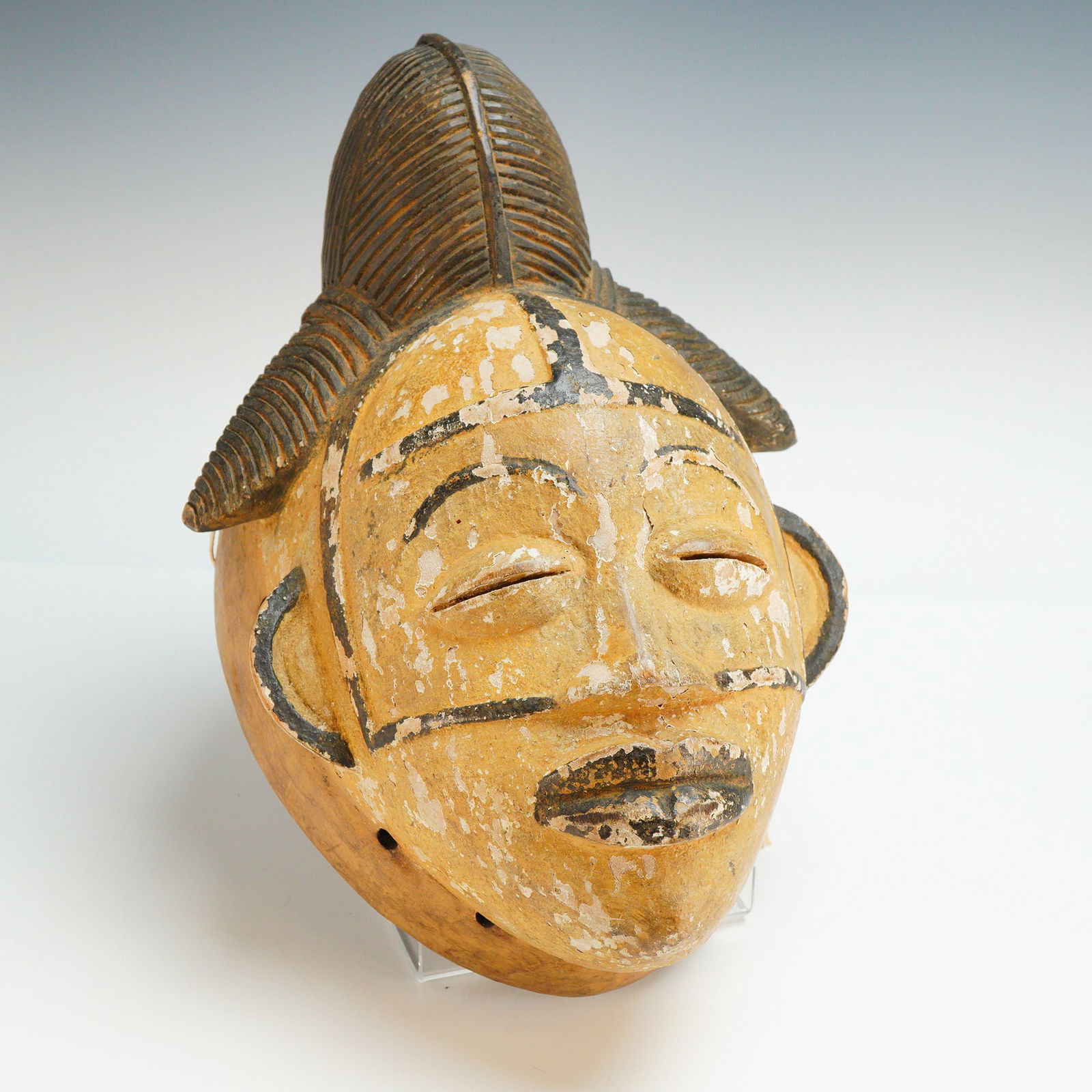 Punu White Faced Carved Wooden Mask: Carved wooden mask from Gabon, traditionally used in Okuyi or Mukudj ceremonies. This hand-carved object is constructed from wood and decorated with white kaolin pigment and black accents. The face