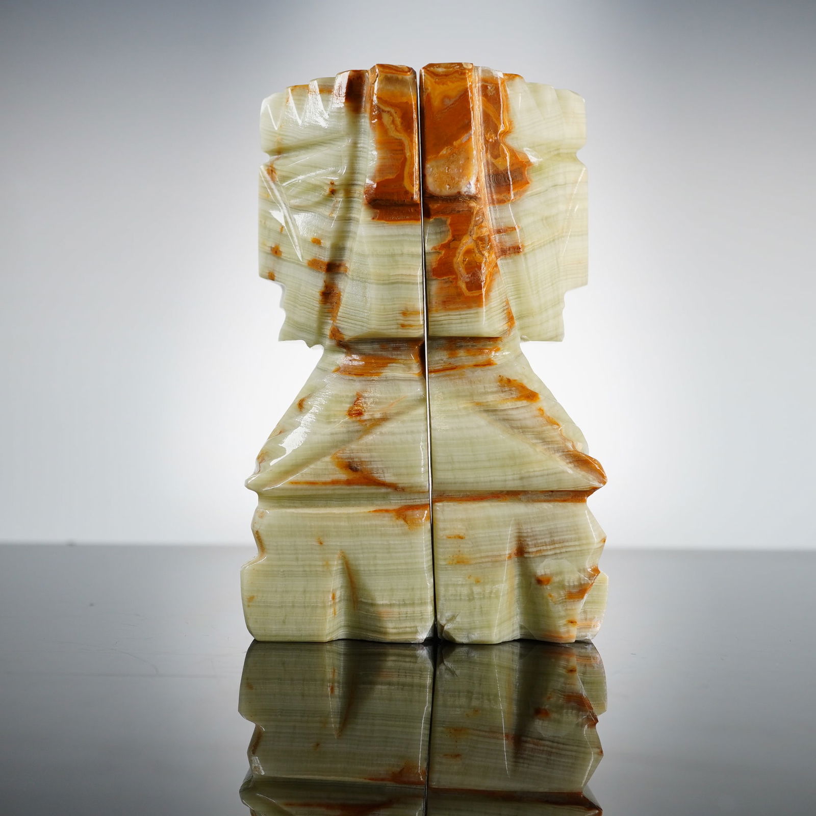 Pair of Vintage Hand Carved Onyx Marble Mayan Stone Bookends: A pair of vintage hand carved onyx marble stone bookends, featuring a stylized Mayan tribal design. Each piece is rendered with geometric, angular features, depicting a figure with a stepped headdress