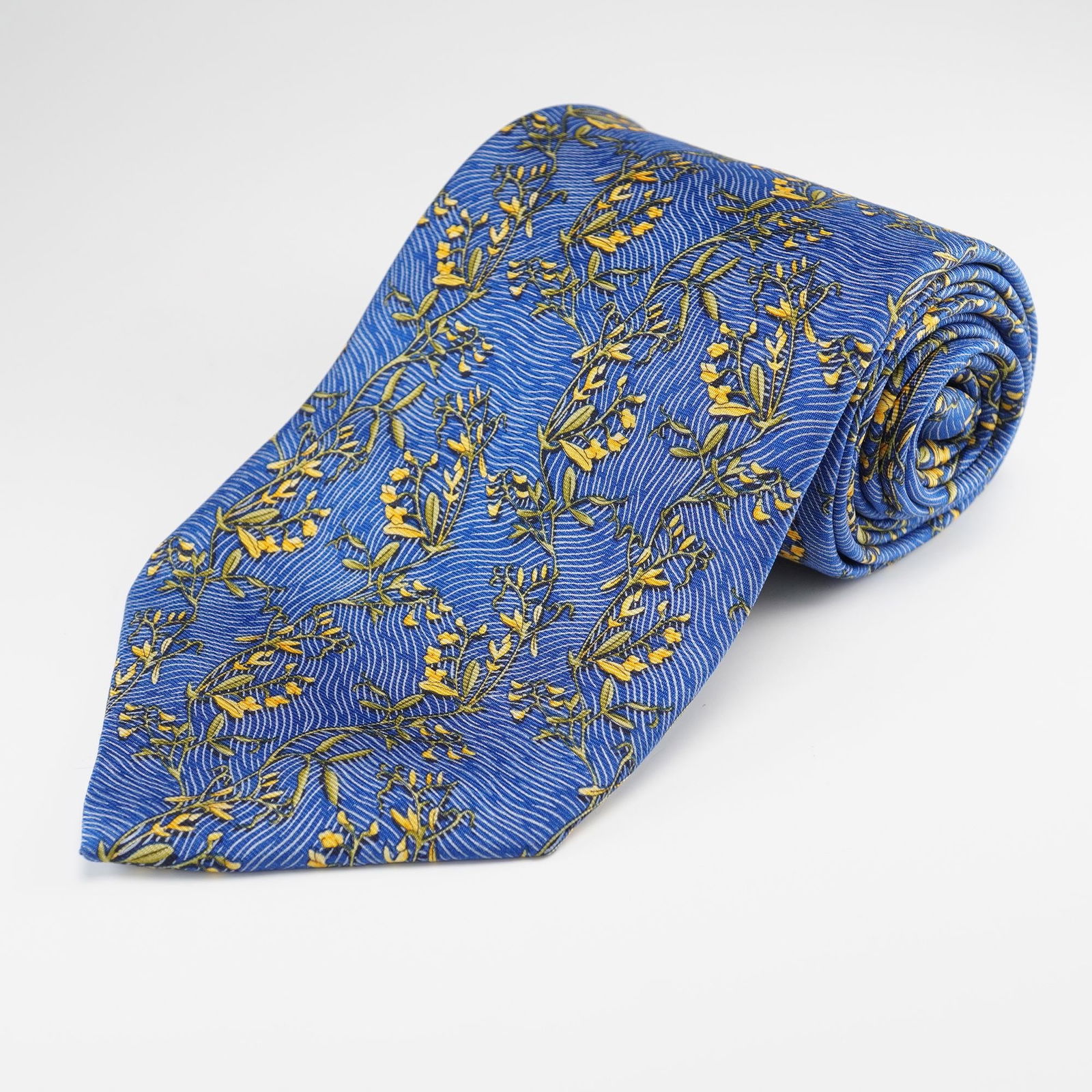 Italian Blue and Yellow Floral Silk Necktie: An Italian silk necktie. Crafted from fine silk, this mens necktie features a vibrant royal blue ground patterned with an all-over repeating motif of delicate yellow flowering branches interspersed wi