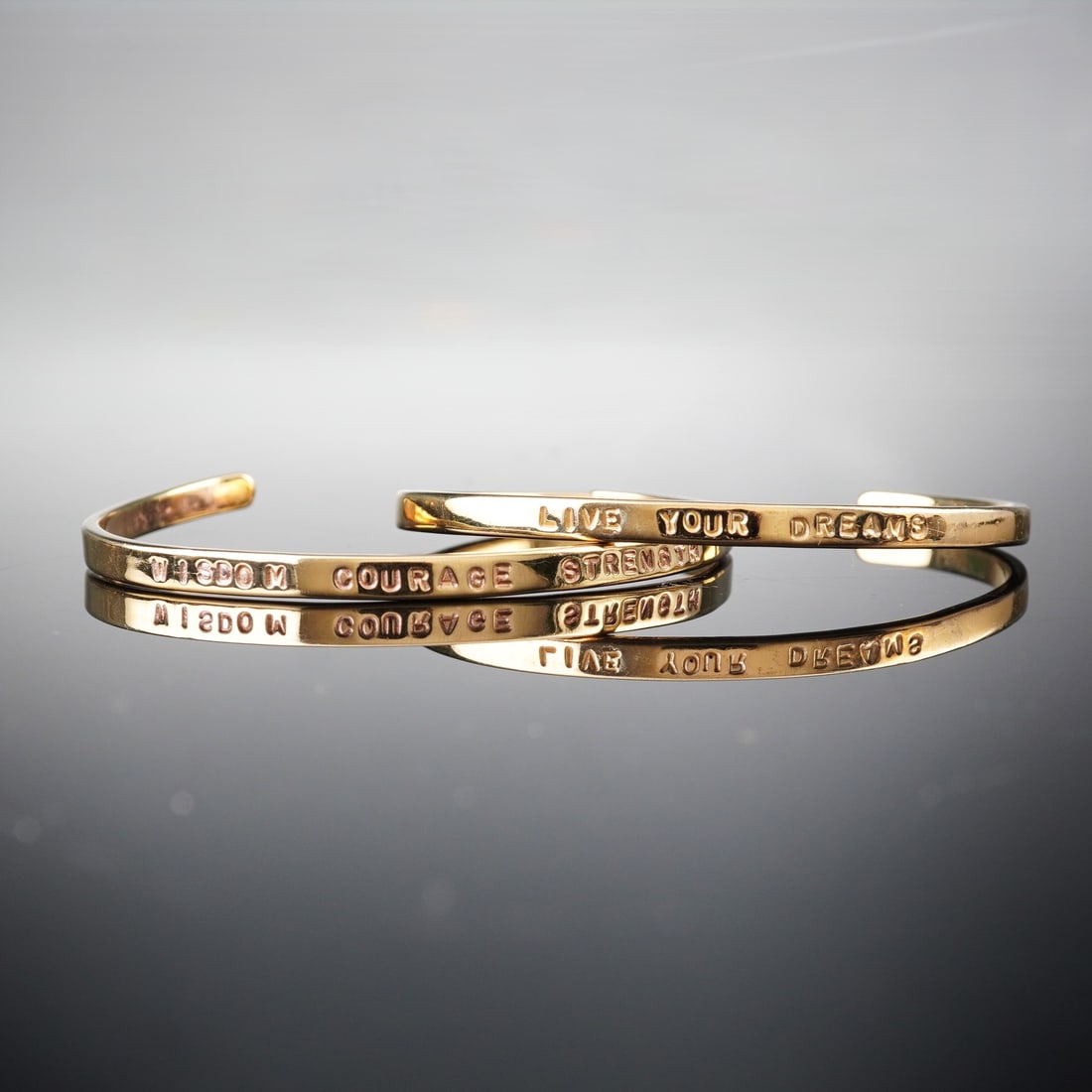 Pair of GK Designs Gold Plated Sterling Silver Mantra Cuff Bracelets: Attributed to GK Designs (Georgianna Koulianos), this duo of modern, minimalist open-cuff bangle bracelets. Each cuff is crafted from Sterling silver, confirmed by the visible hallmark, and finished w