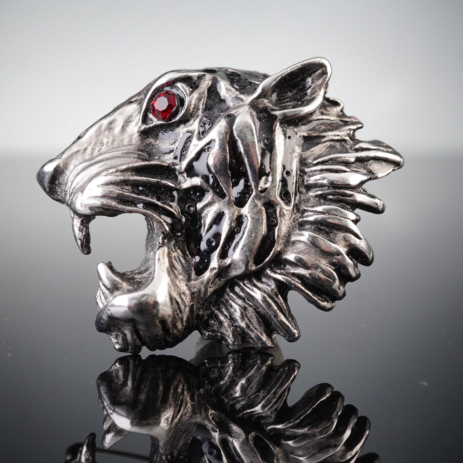 Giorgio Armani Silver Tone Tiger Head Brooch Pin: A Giorgio Armani silver tone tiger head brooch pin. Crafted in an animalier style, depicting a roaring tiger head with an open mouth, fangs, and a textured mane. A single round red stone is set in one