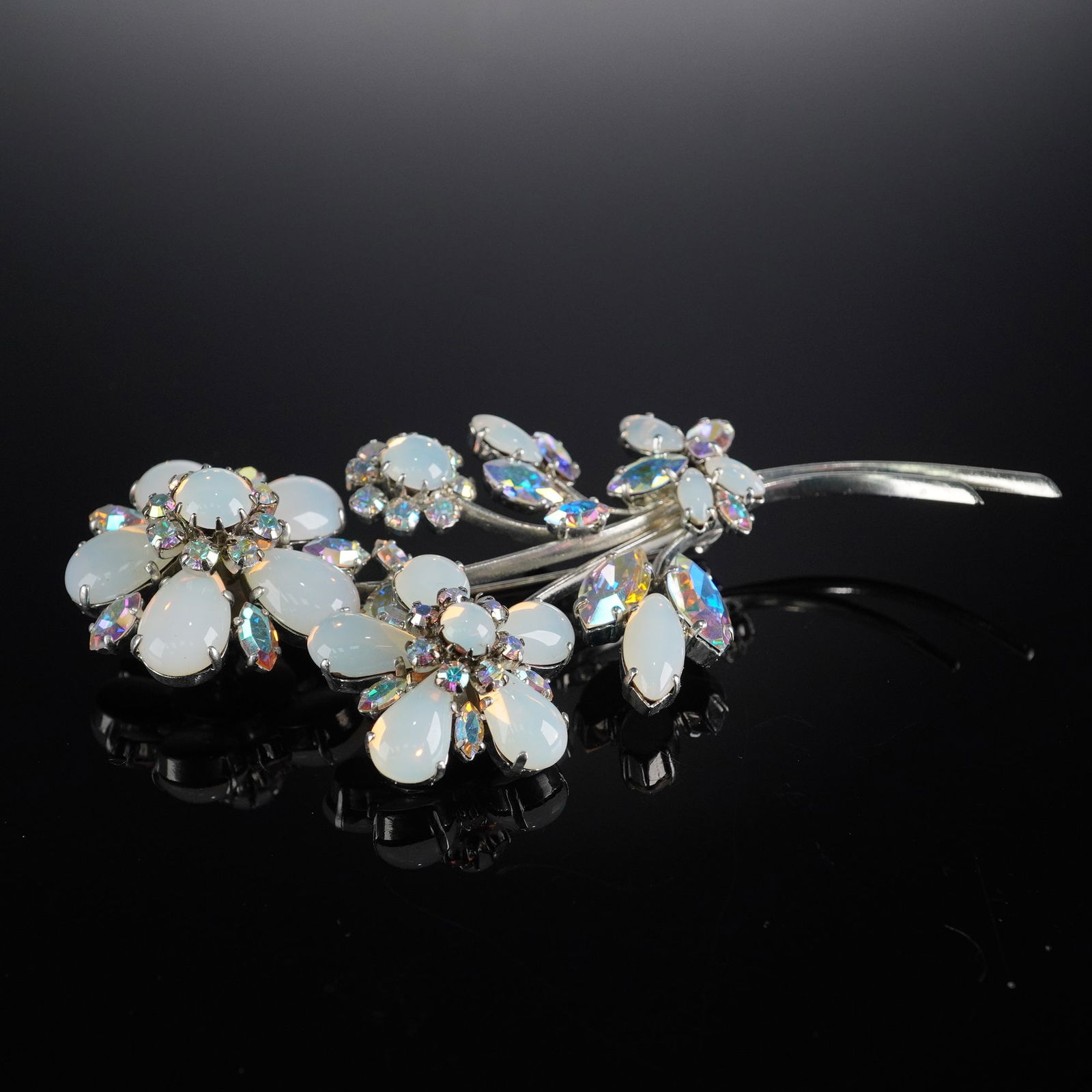 Silver-Tone Flower Spray Brooch with Moonstone & AB Stones: A Coro silver-tone flower spray brooch, adorned with multiple white opaque cabochon-style stones, likely glass, in teardrop and oval shapes, surrounded by smaller, faceted iridescent rhinestones exhib