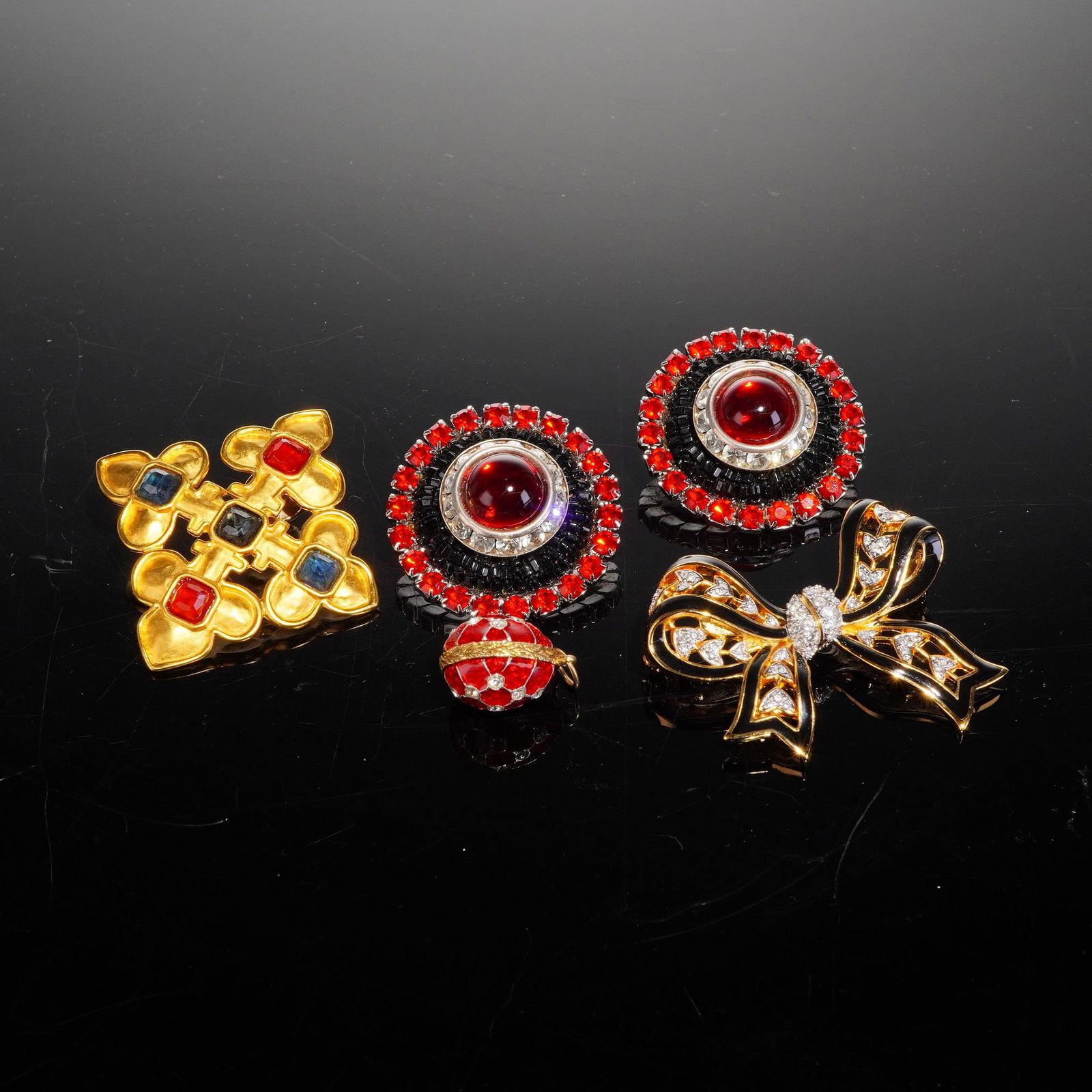4pc Mixed Gold-Tone Costume Jewelry: A collection of late 20th-century mixed costume jewelry, which includes a highly stylized bow brooch, a pair of circular clip-on earrings, a geometric cross-form pin, and a small spherical pendant. Th