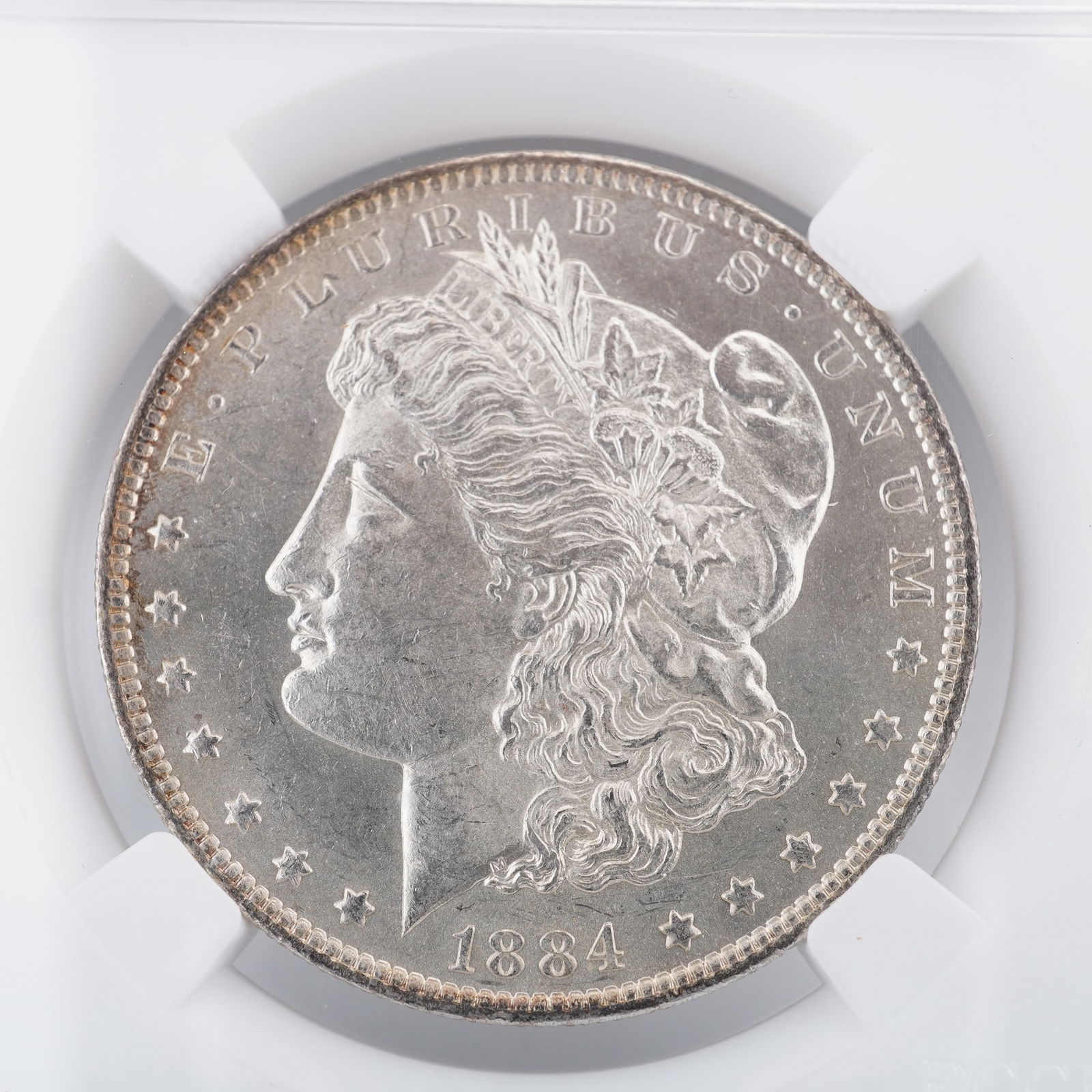 1884-O Morgan Silver Dollar: Featured is an 1884-O Morgan Silver Dollar, struck at the New Orleans Mint and composed of ninety percent silver. The obverse displays George T. Morgan's renowned rendition of Liberty, crowned with a