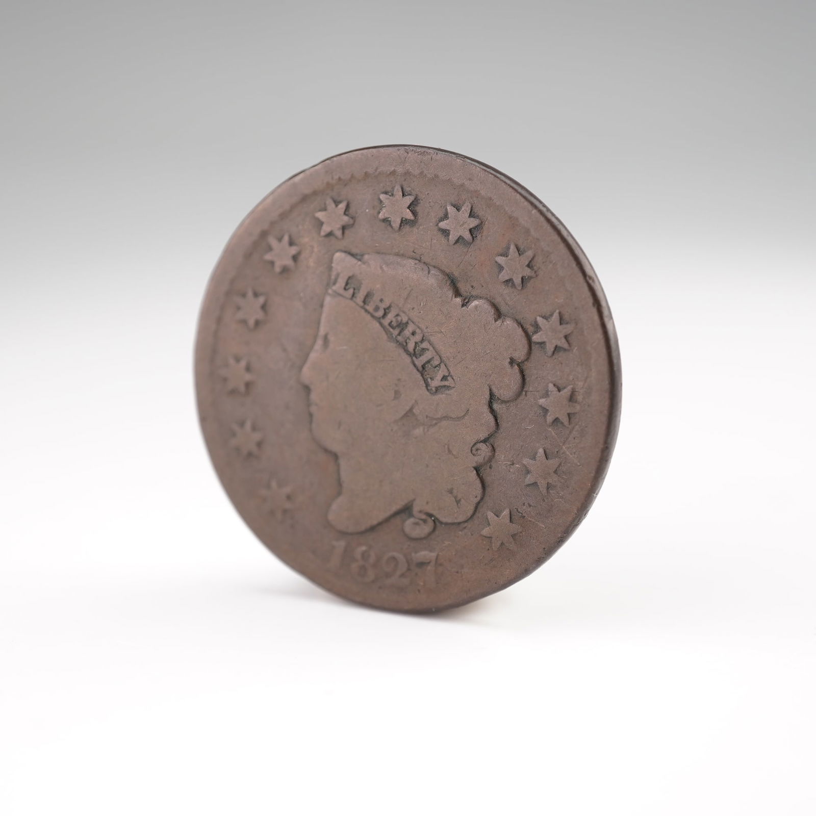 1827-(P) Liberty Head Type 1 Matron Head 1 Cent Coin: Struck at the Philadelphia Mint, this large cent features the Classic Head design with a left-facing portrait of Liberty wearing a headband inscribed LIBERTY, encircled by thirteen stars with the date