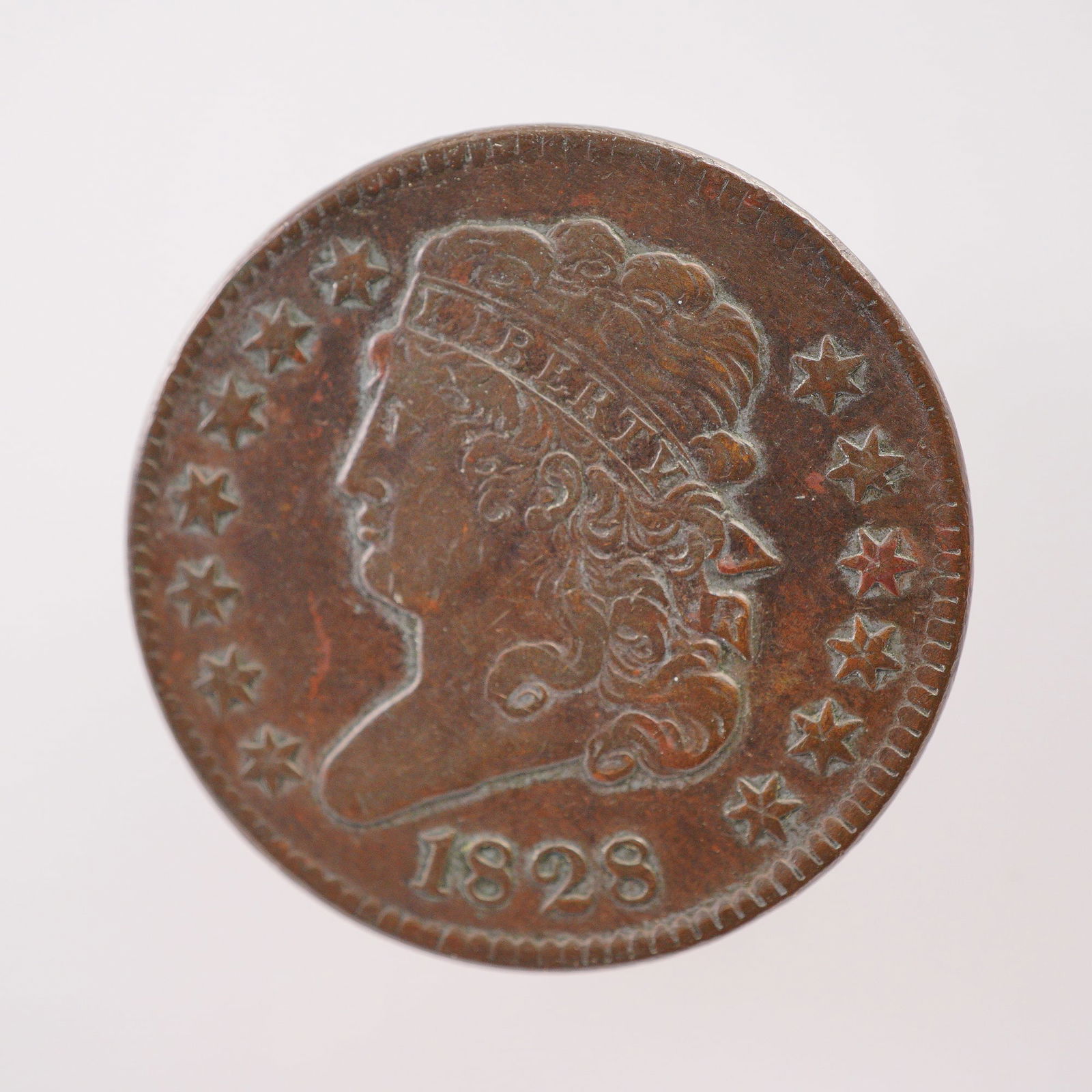 1828 United States Classic Head Half Cent Coin: Compose of copper, the obverse features the Classic Head portrait of Liberty facing left with finely detailed curls and a boldly rendered LIBERTY, thirteen stars, and the year below. The reverse displ