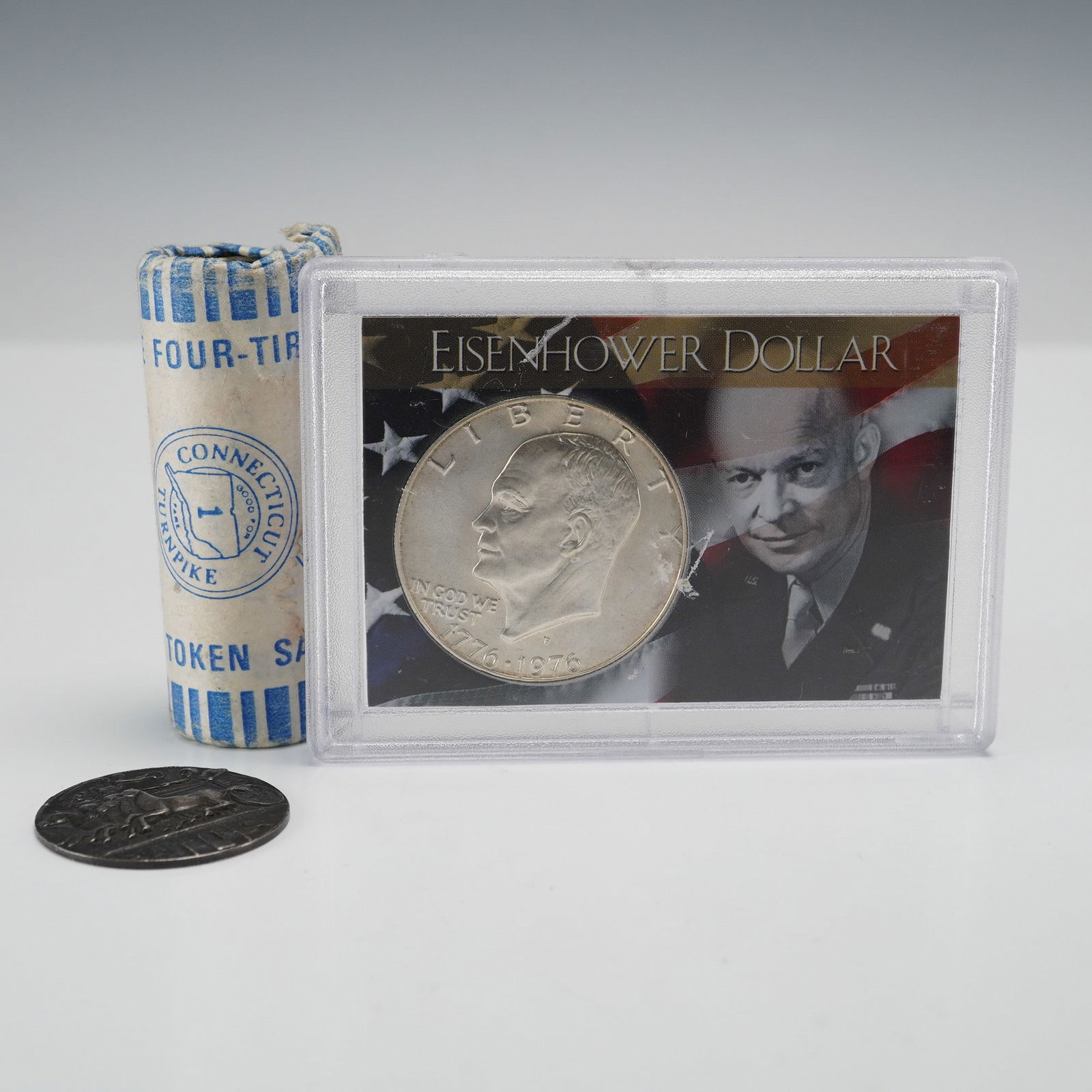 3pc 1976 Eisenhower Silver $1, Connecticut Turnpike Tokens & Replica Coin: Mixed numismatic and exonumia lot including a 1976 Eisenhower Bicentennial Silver Dollar, a full roll of 40 Connecticut Turnpike tokens, and a replica Syracuse coin stamped STERLING on the reverse. Th