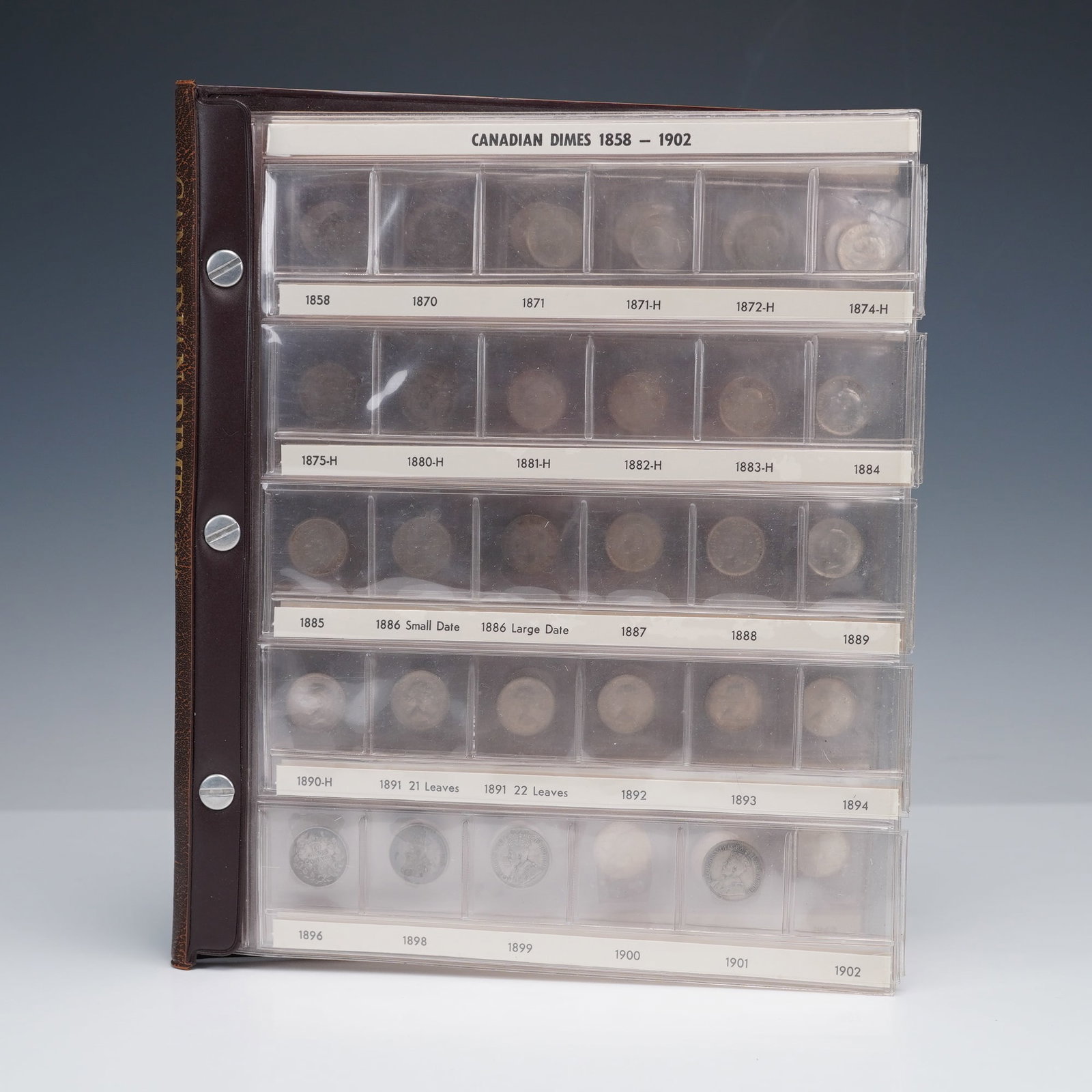77pc 1929 to 2004 Bound Canadian Dimes: Presented in a sturdy brown album with labeled slots for each year. The 77 coin set features classic designs including the portrait of Queen Elizabeth II on the obverse with the inscription "ELIZABETH