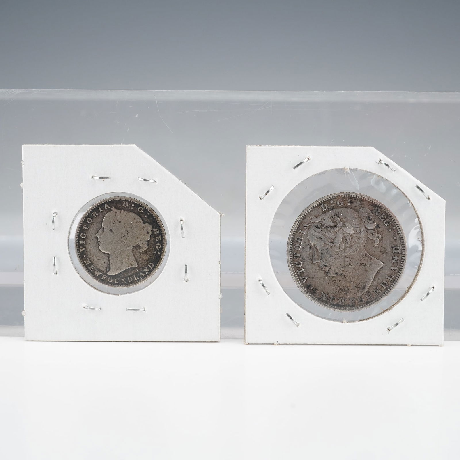 2pc Newfoundland Silver Coins, 1873 10C & 1881 20C: A pair of silver coins issued for the Colony of Newfoundland under Queen Victoria, including the 1873 10 Cents and the 1881 20 Cents. Both coins feature the Young Head obverse type. Both house in prot