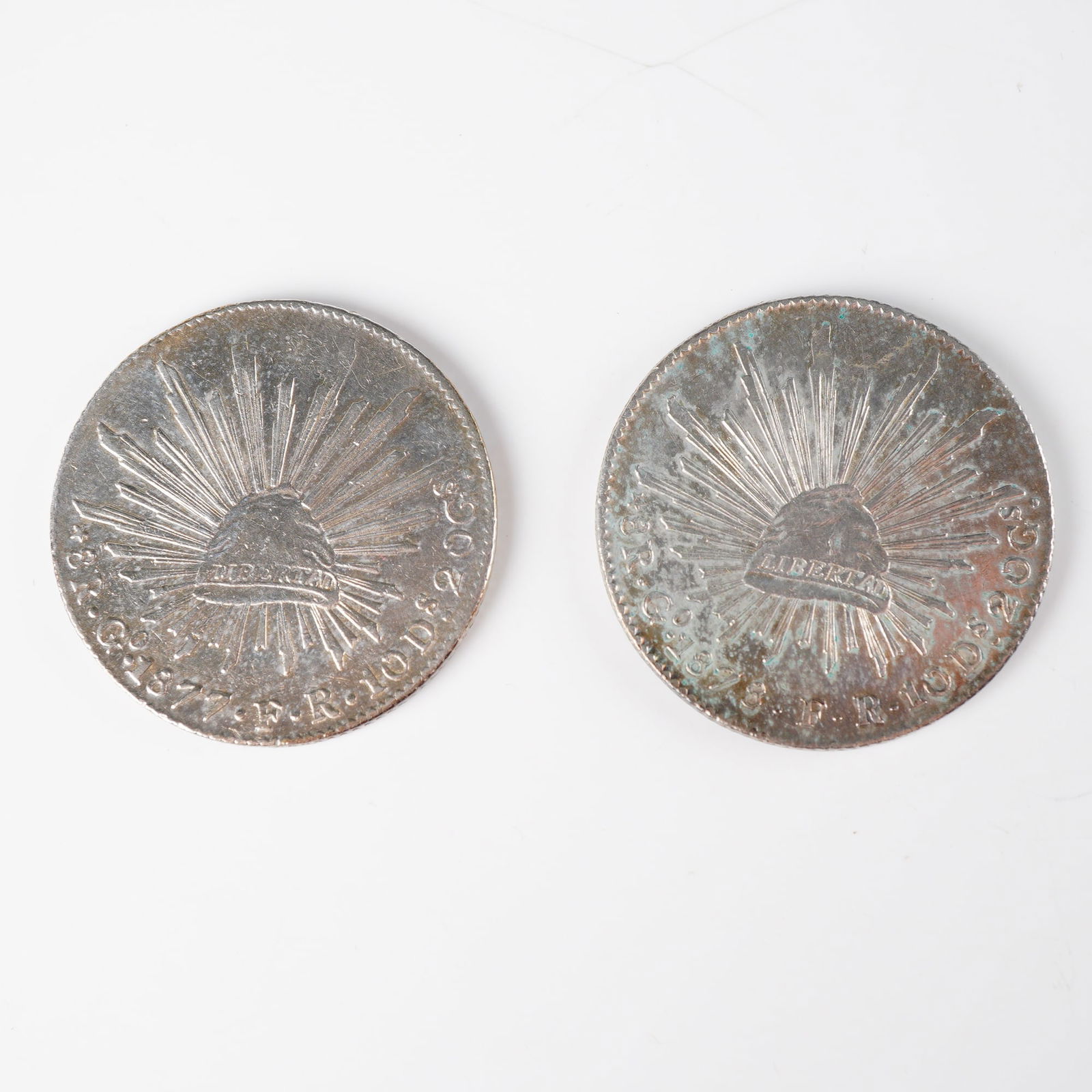 Pair of 1877 & 1878 8 Reales Coins from Mexico: A pair of 8 Reales silver coins from Mexico, including years 1877 and 1878, issued during the Second Republic period. The design features the National Eagle obverse and the Radiant Cap of Liberty reve