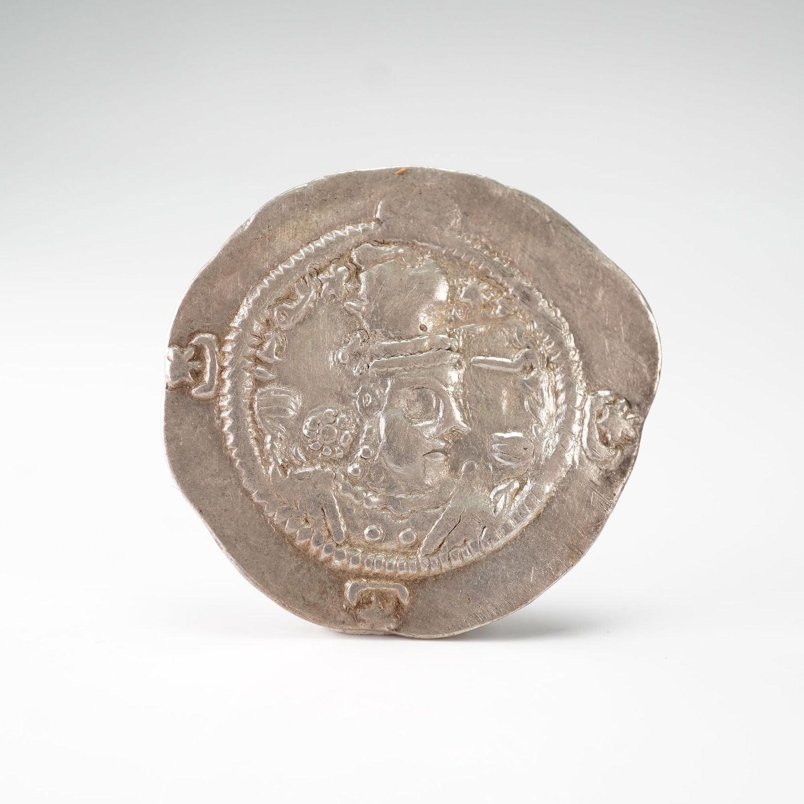 579 to 590 Sasanian Hormizd IV AR Drachm: Silver drachm depicting on the obverse a right-facing bust of King Hormizd IV wearing a crenellated crown with a korymbos and adorned with ribbons, surrounded by a dotted border and Pahlavi inscriptio