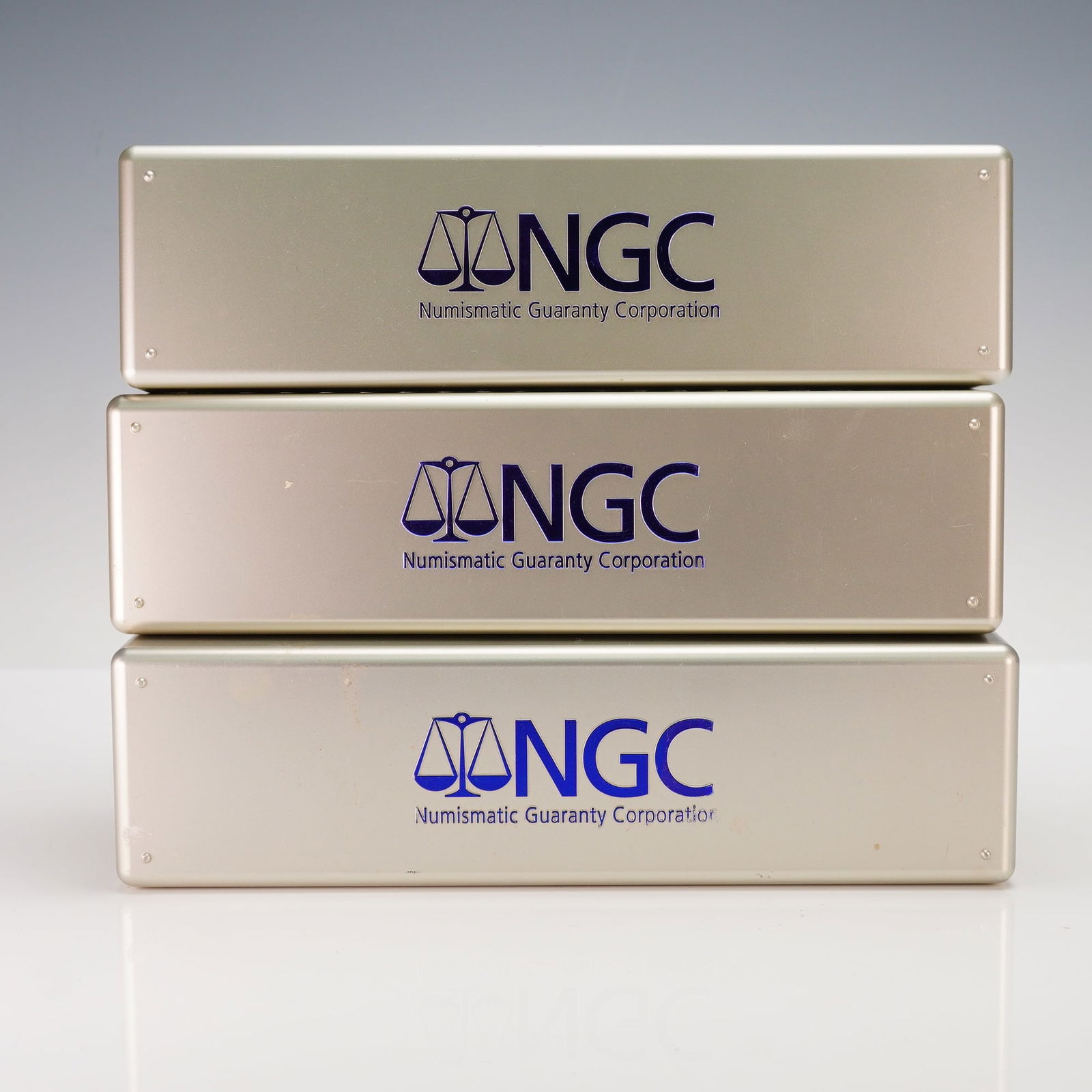 Trio of NGC Silver Plastic Slab Storage Boxes (Holds 60 Total): A trio of empty storage boxes officially manufactured by the Numismatic Guaranty Corporation (NGC) for the secure storage and transport of certified numismatic slabs. These standard boxes feature a si