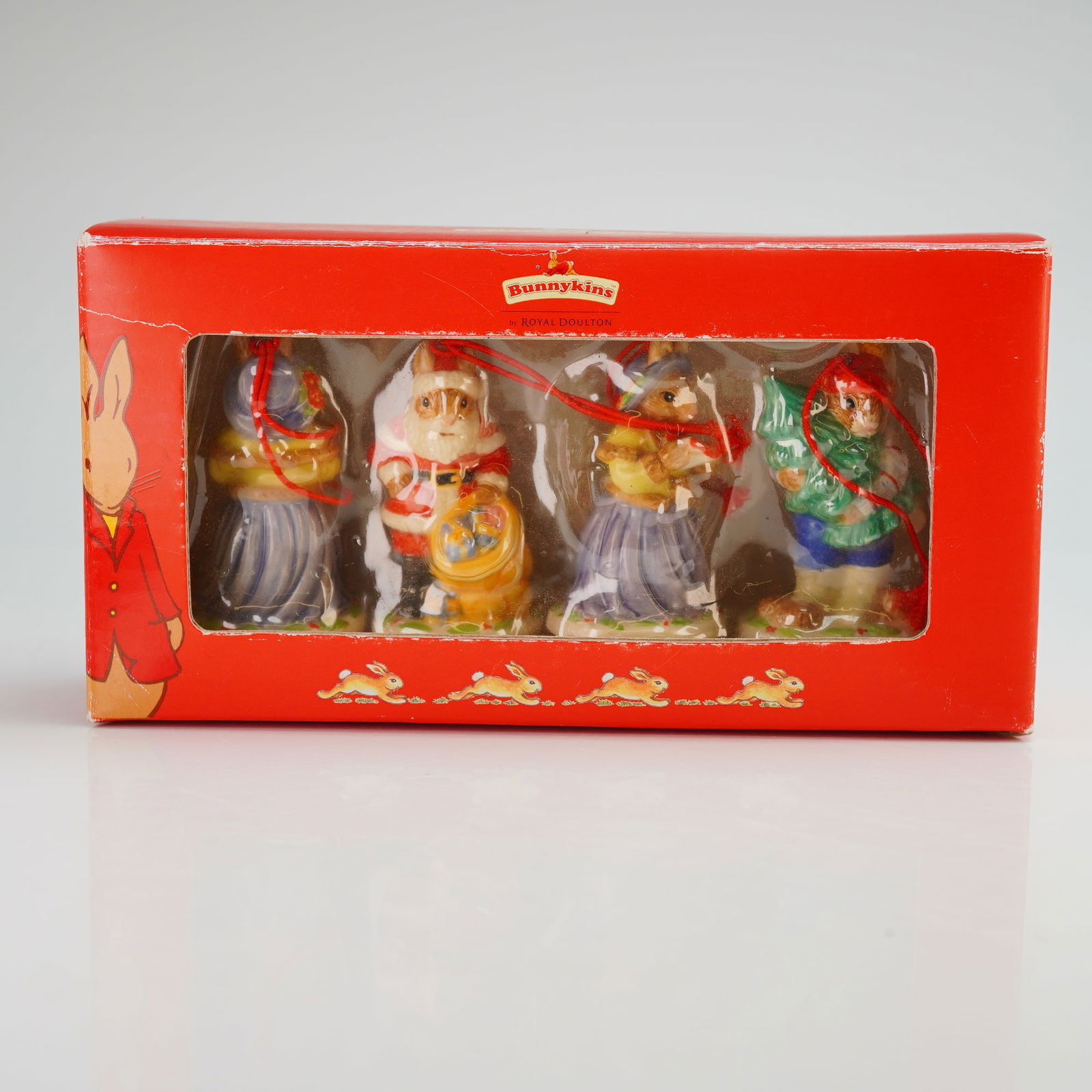 A Collection of Royal Doulton Porcelain Bunnykins Christmas Ornaments: This collection of Royal Doulton porcelain Bunnykins ornaments is from the Christmas Collection and features glazed ceramic figurines of anthropomorphic rabbits. The set includes figures such as