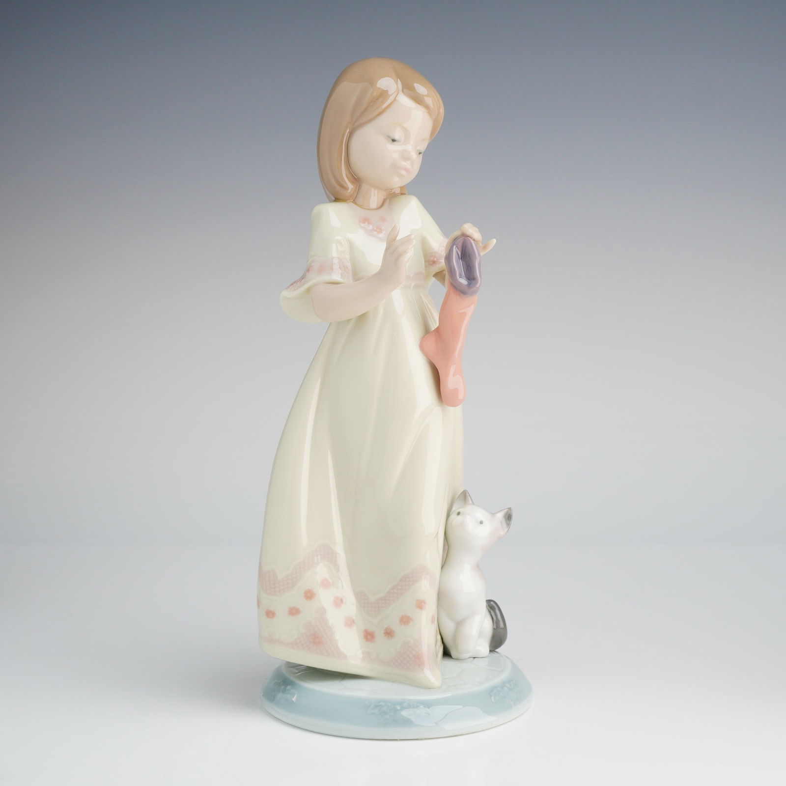 Lladro Stocking For Kitty Figurine 6669: A Lladro glazed porcelain figurine, model number 6669, titled "A Stocking For Kitty," part of "THE NIGHT BEFORE CHRISTMAS COLLECTION." The figurine depicts a young girl in a long, cream-colored nightg