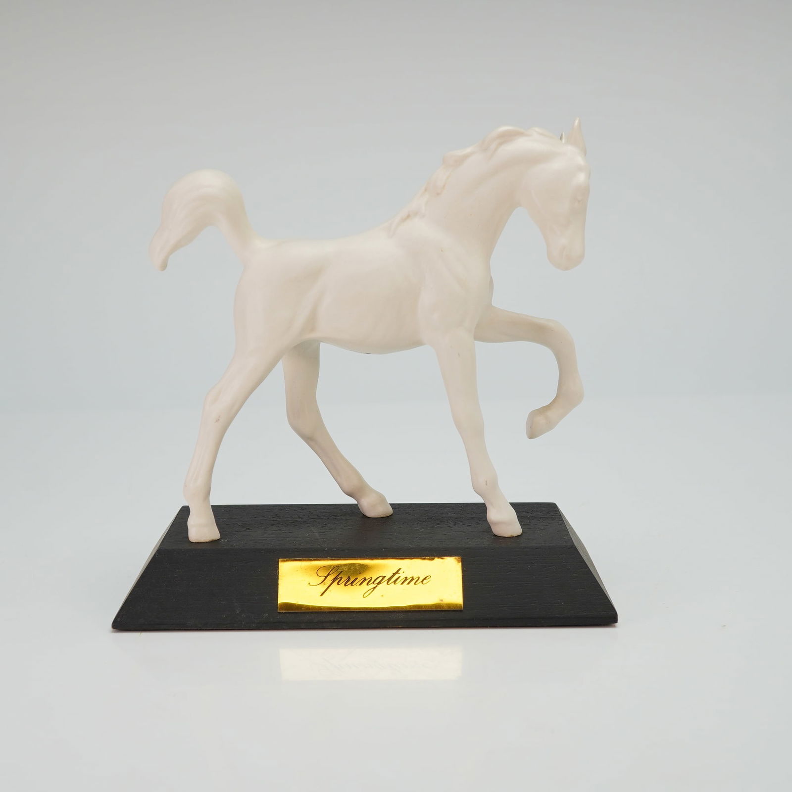 Beswick Springtime Matte White Horse Figurine on Base: The piece is rendered in a matte white finish and depicts a foal in a prancing pose with the front left leg raised. The sculpture features stylized, flowing details on the mane and tail. It is mounted