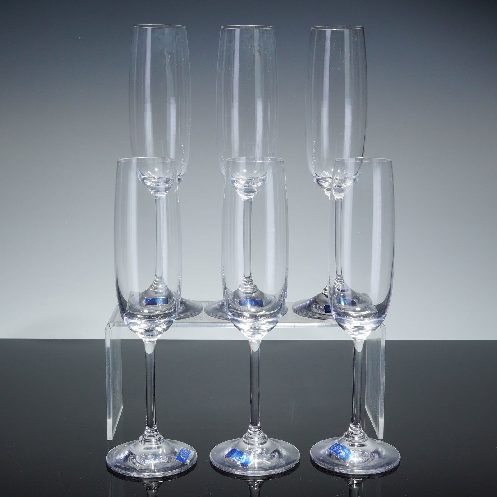 6pc Marquis by Waterford Crystal Champagne Flutes, Vintage: A set of six crystal champagne flutes from the Marquis by Waterford line in the Vintage pattern. Each piece features a sleek, elongated bowl on a slender, tapered stem and a wide circular base. The cl