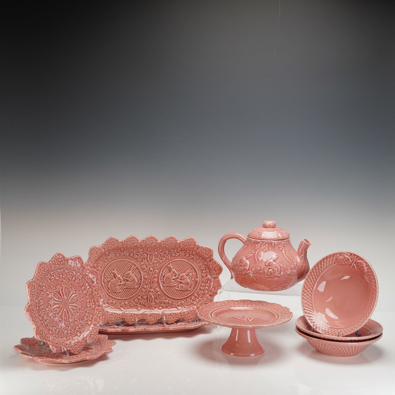9pc Bordallo Pinheiro Ceramic Tableware, Pink Rabbit: A collection of nine items including one lid, totaling ten pieces, of Portuguese earthenware ceramic tableware by Bordallo Pinheiro, executed in a high-gloss dusty rose or coral pink glaze. The pieces