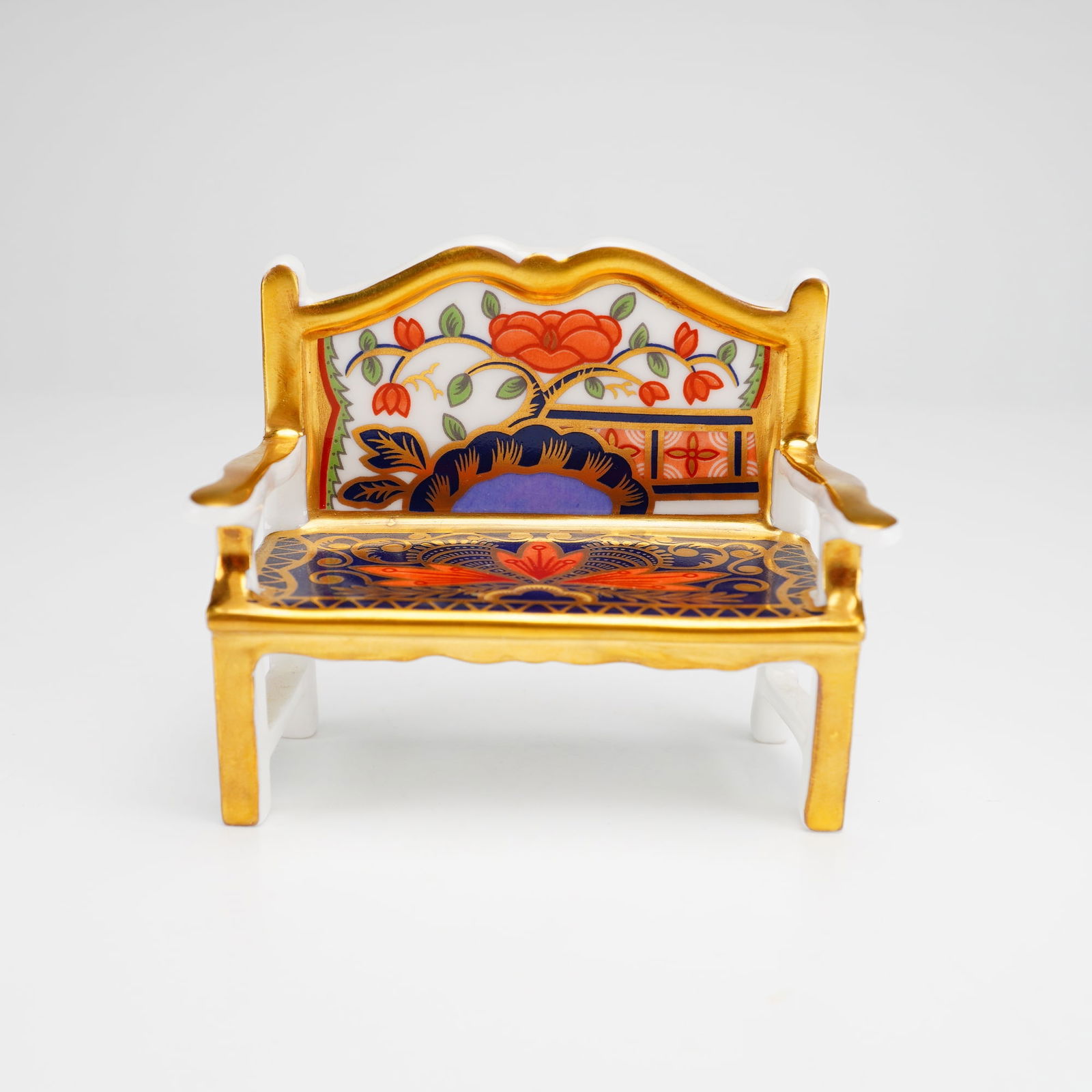 Royal Crown Derby Bone China Imari Paperweight, Garden Bench: The piece is decorated in the Old Imari pattern, featuring a palette of cobalt blue and iron red with gold gilded highlights. The design incorporates stylized floral and geometric motifs across the se