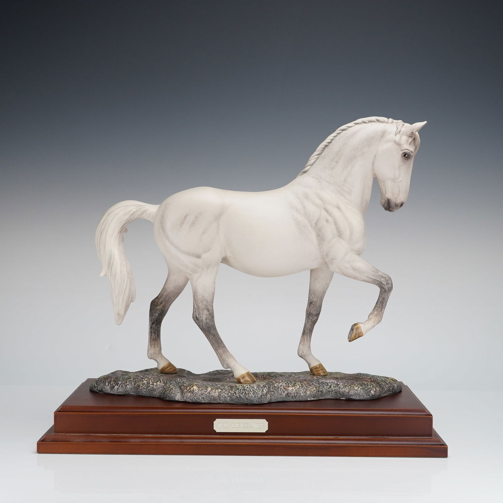 Royal Doulton Figurine, The Lipizzaner DA 243: A Royal Doulton figurine titled "The Lipizzaner," depicting a white and greyish-white horse in a dynamic, stylized pose. The figurine is hand made and hand decorated, standing upon a textured ground m