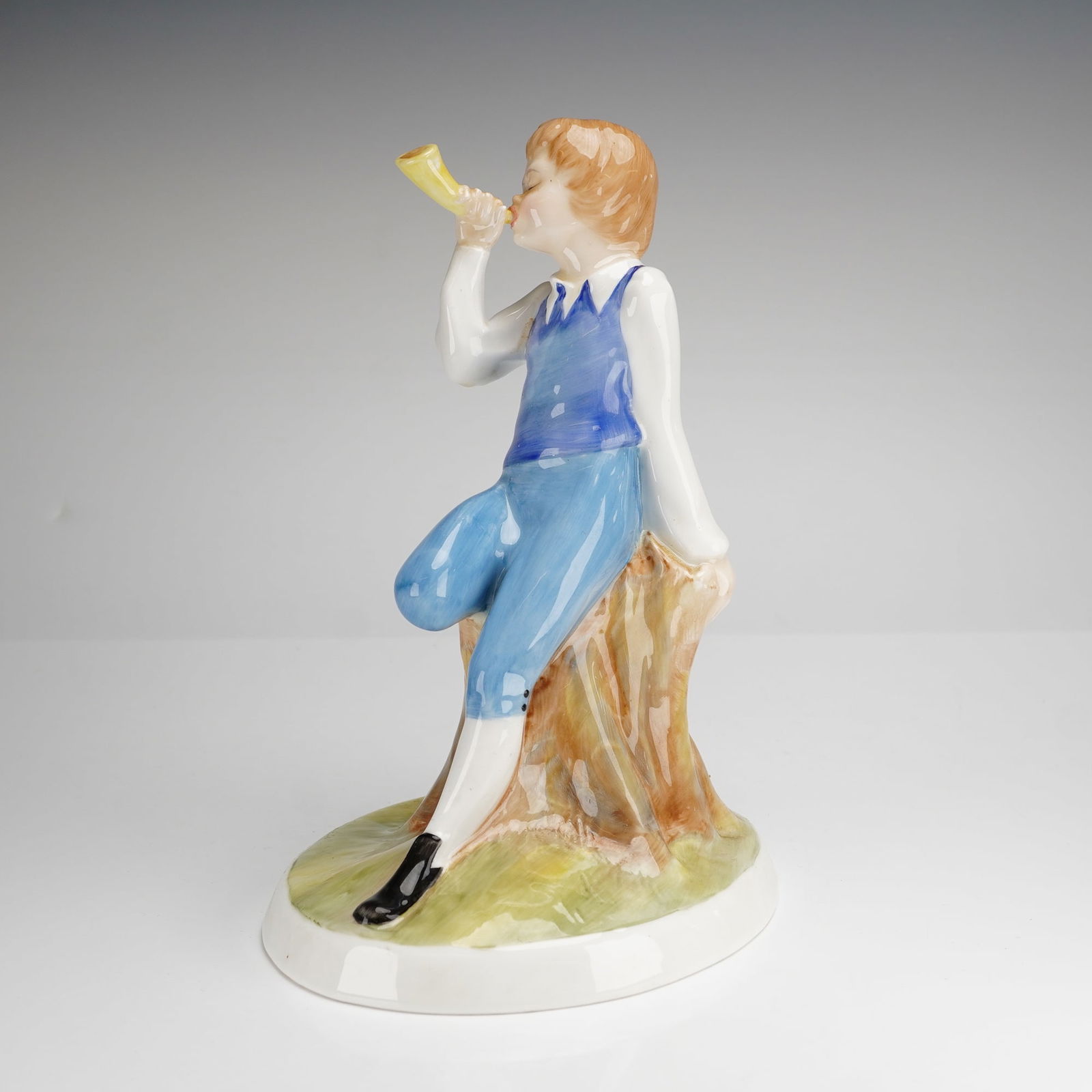 Royal Doulton Nursery Rhymes Collection Little Boy Blue Figurine HN3035: A Royal Doulton bone china figurine from the Nursery Rhymes Collection titled Little Boy Blue, model HN3035. This hand-decorated figure was modeled by Adrian Hughes and is dated 1983. The piece depict