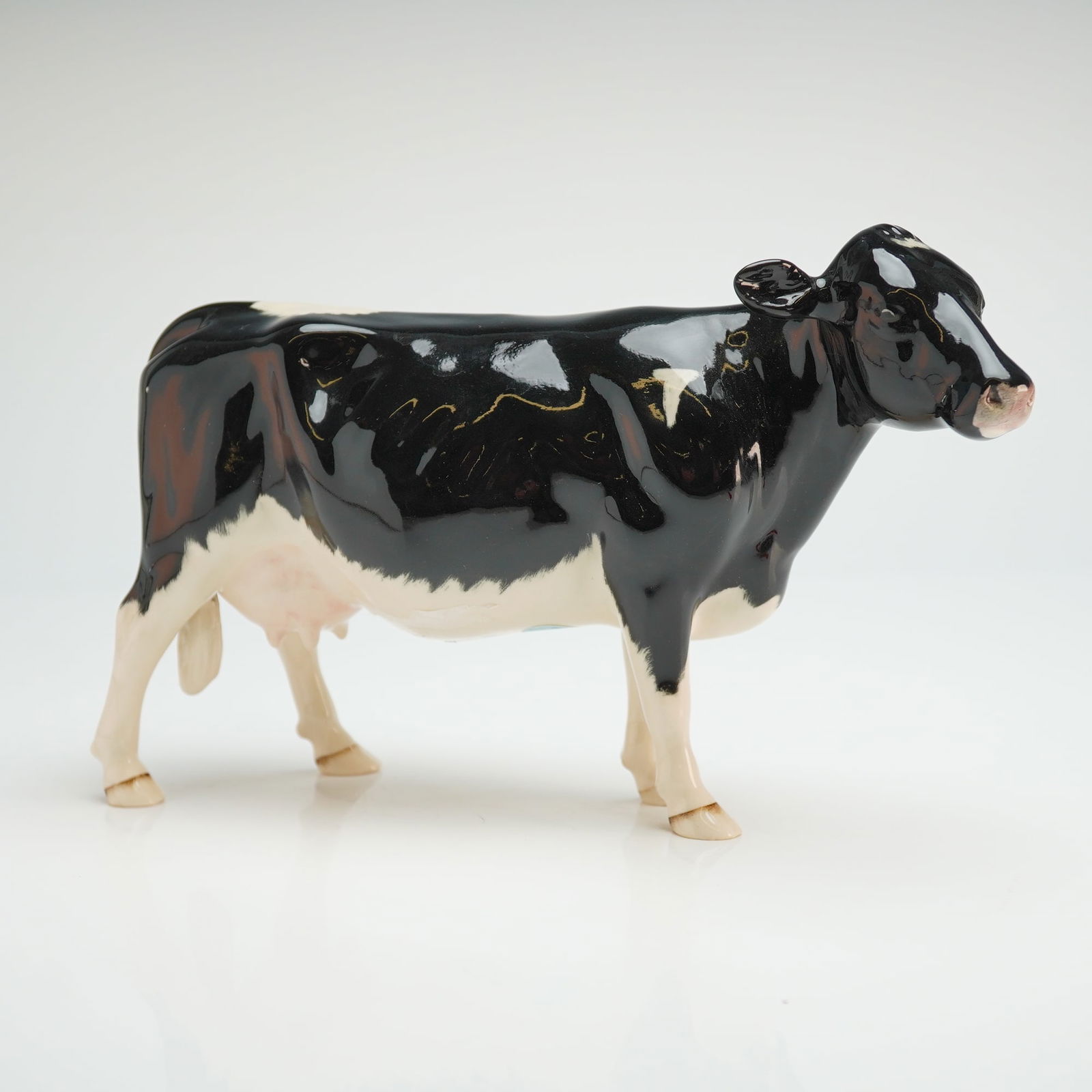 Beswick England Friesian Dairy Cow Champion Claybury Leegwater Figurine: This Beswick figurine depicts a Friesian dairy cow, identified by market consensus as the Champion Claybury Leegwater model, number 1362. The glazed ceramic figure is rendered in a standing pose with