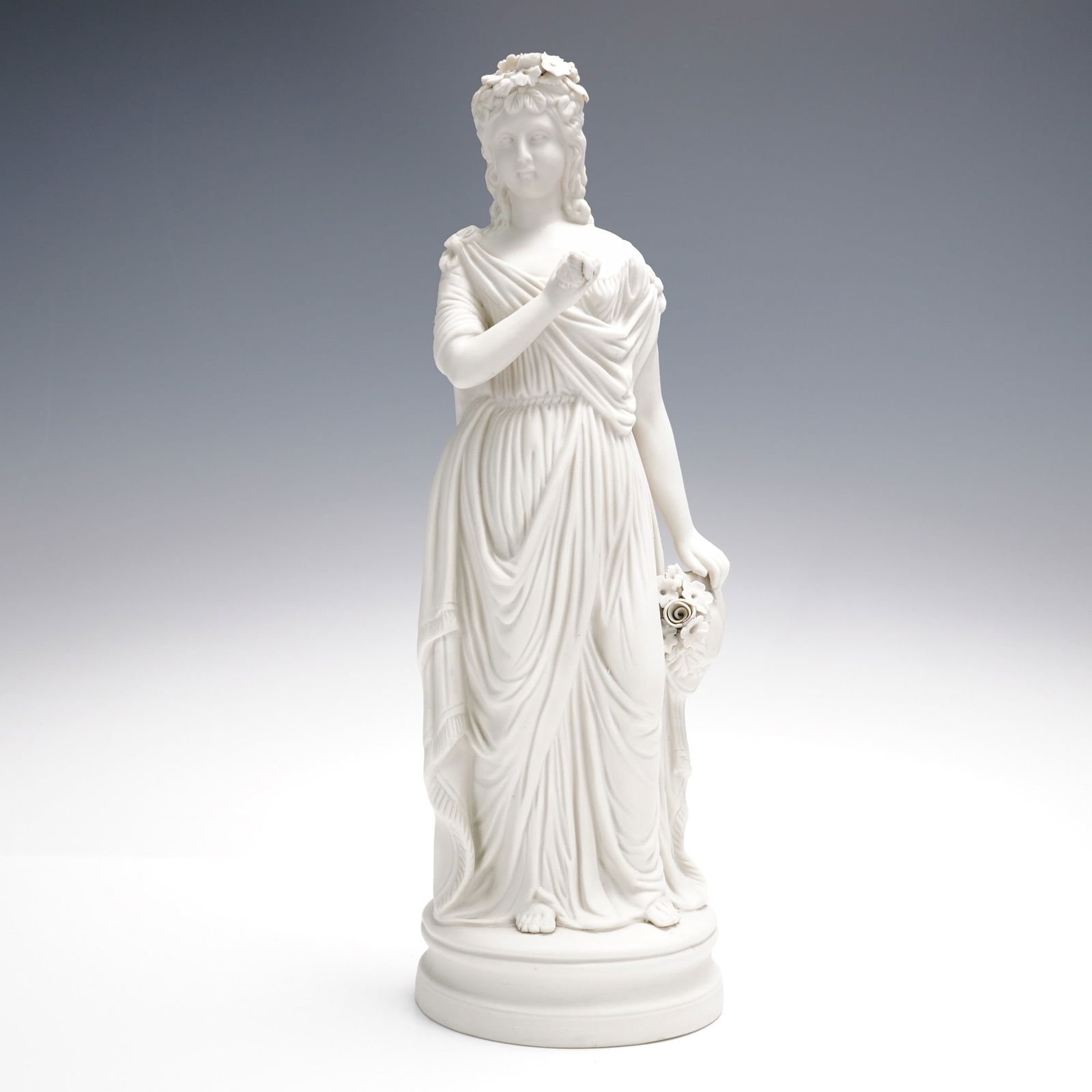 Continental White Bisque Figure of a Classical Maiden with Floral Garland: Graceful 14-inch Continental white bisque porcelain sculpture of a standing classical maiden adorned with a floral crown and flowing drapery. She delicately holds a garland of roses in one hand, evoki