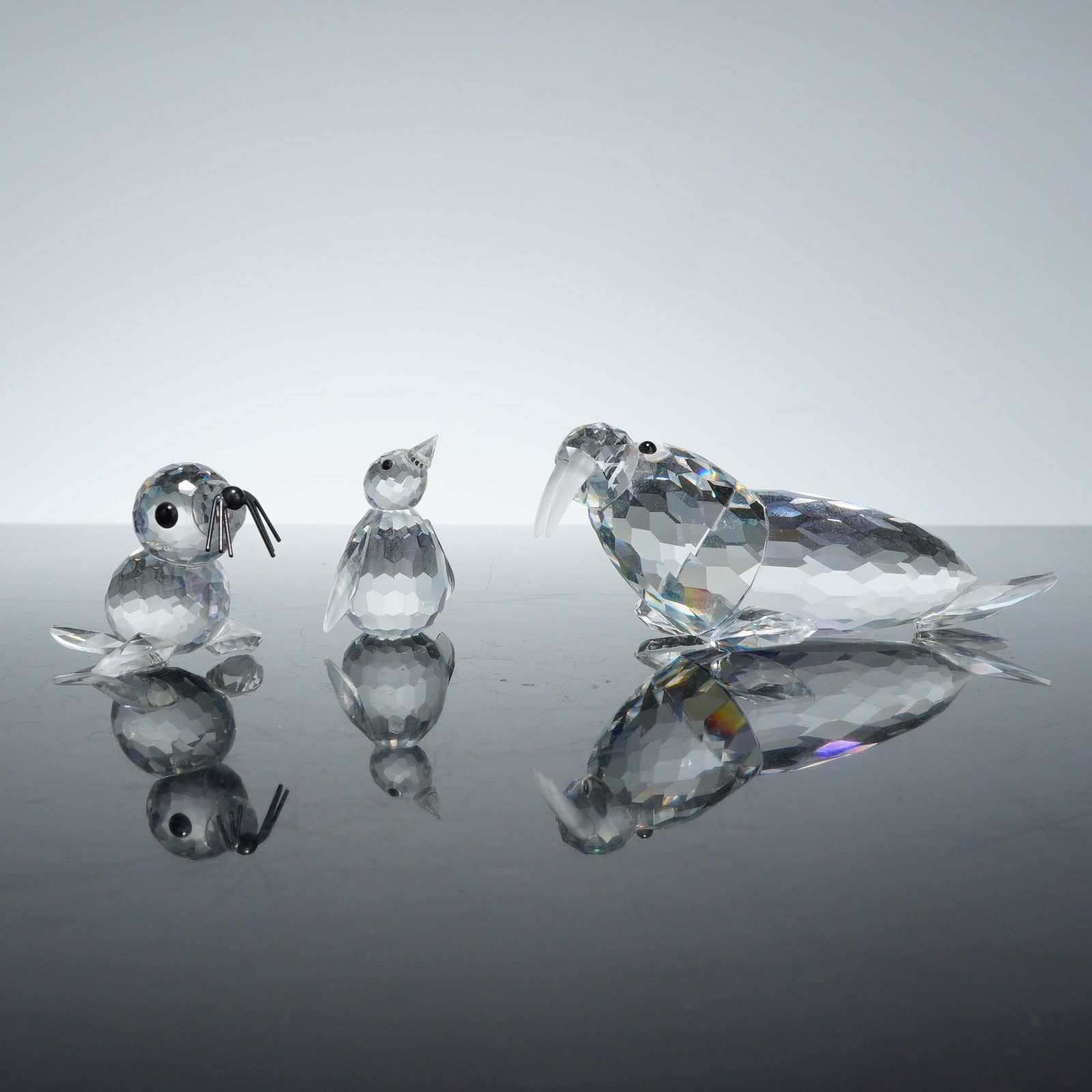 3pc Swarovski Crystal Ice Animals Figurines, Walrus, Penguin and Baby Seal: Three Swarovski crystal ice animals figurines, including a walrus, a penguin, and a baby seal. Each piece is constructed from clear, highly faceted lead crystal. The walrus features frosted tusks and
