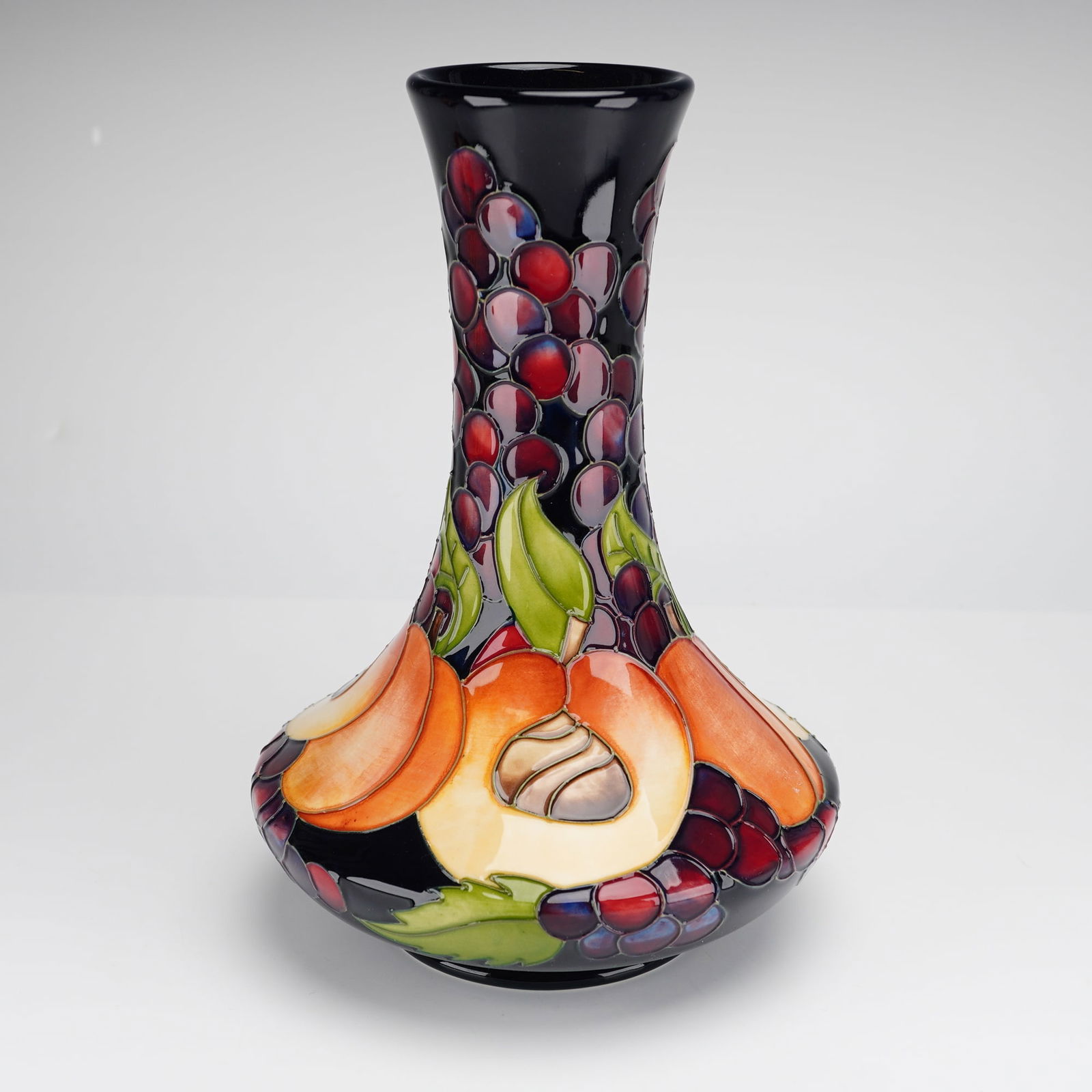 Moorcroft Autumn Apricot Limited Edition Signed Vase: A Moorcroft pottery vase in the Autumn Apricot pattern, featuring a bulbous base and a slender neck with a flared rim. The piece is decorated with a tube-lined design showcasing apricots and clusters