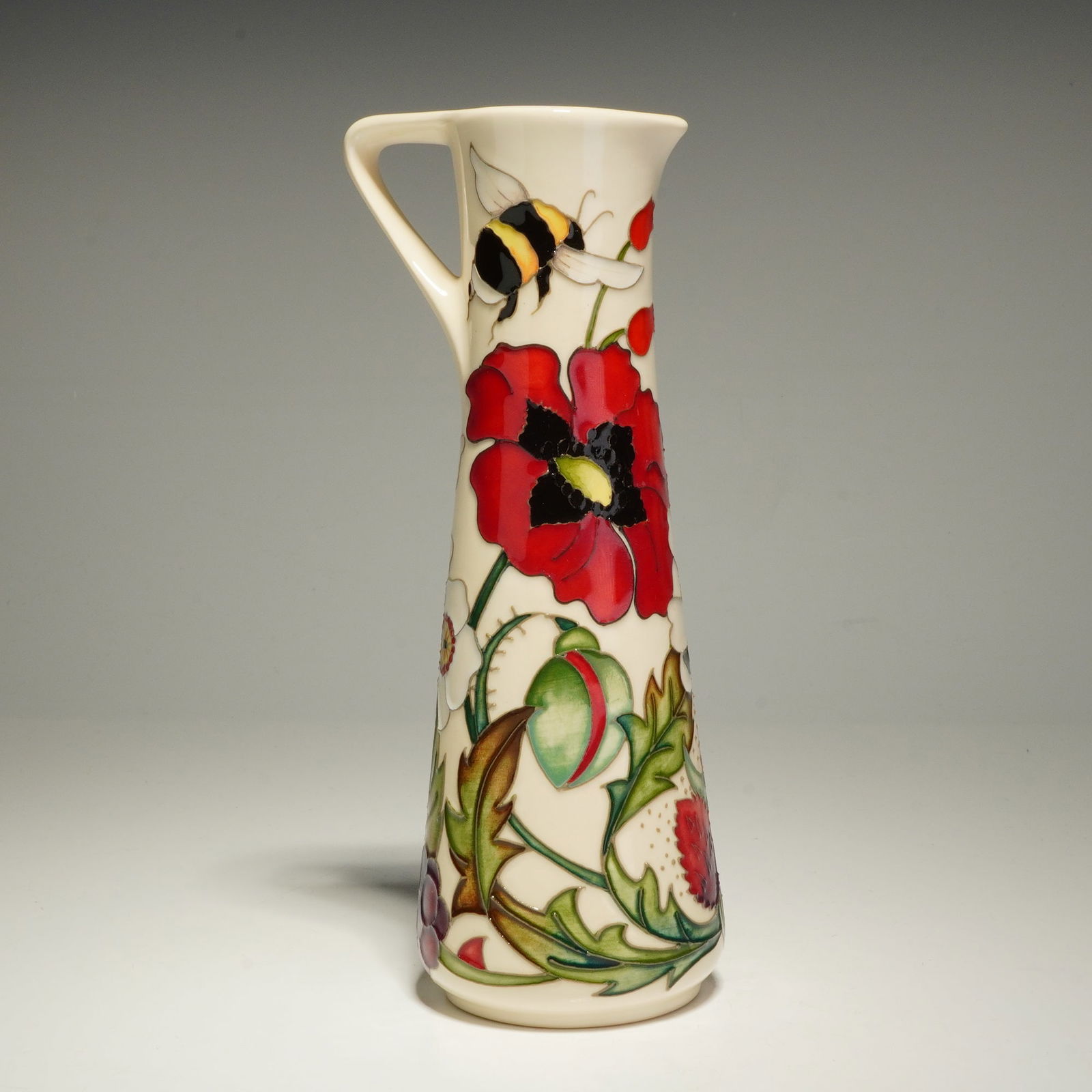 Moorcroft The Pollinators JU7 Jug: A Moorcroft ceramic jug in The Pollinators pattern, shape JU7, designed by Rachel Bishop. The vessel features a tapered, conical body with a single angular handle and a small spout. The exterior is