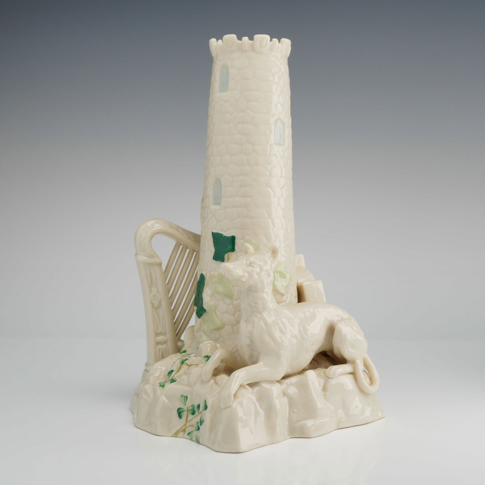 Belleek Porcelain Spill Vase, Emblems of Ireland, Tower Harp: This Belleek Parian porcelain spill vase is modeled in the Emblems of Ireland pattern, featuring a central round tower with a crenelated rim and textured masonry. The base is composed of a rocky