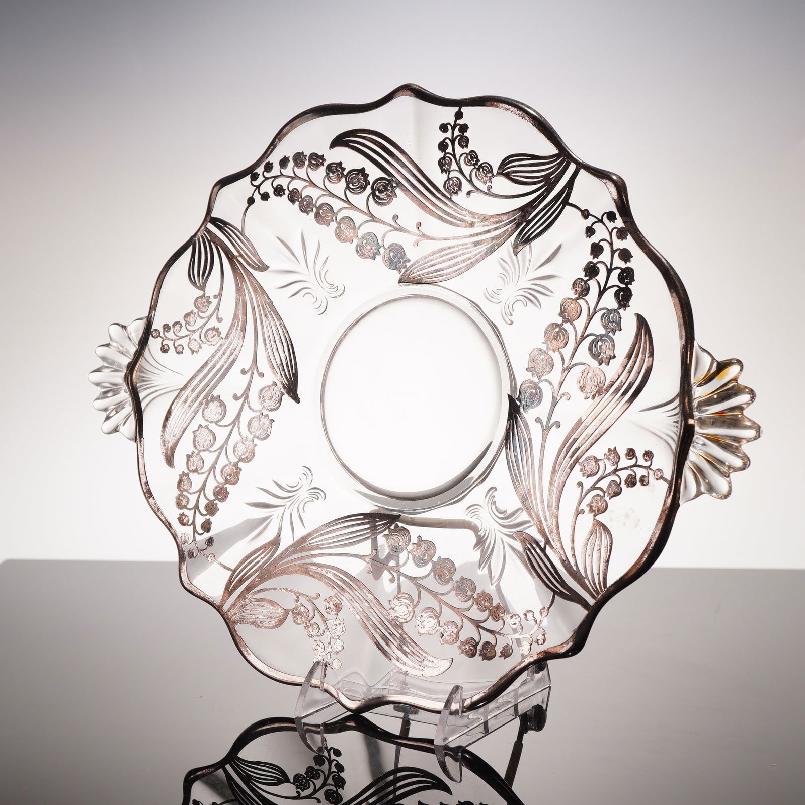 Silver Overlay Lily of the Valley Motif Glass Serving Platter: An early 20th-century glass featuring a scalloped rim and two integral shell-form handles. The interior is decorated with elaborate sprays of silver overlay in a Lily of the Valley motif, interspersed