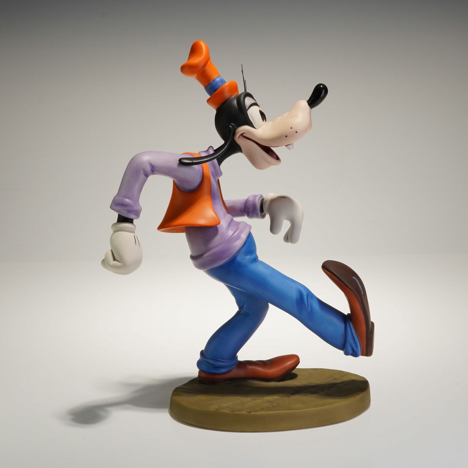 Walt Disney Classics Collection Goofy Moving Day 1997: A porcelain collectible figurine from the Walt Disney Classics Collection, titled "Oh, The World Owes Me A Livin' Moving Day." This piece depicts the character Goofy in a dynamic stride, rendered in a