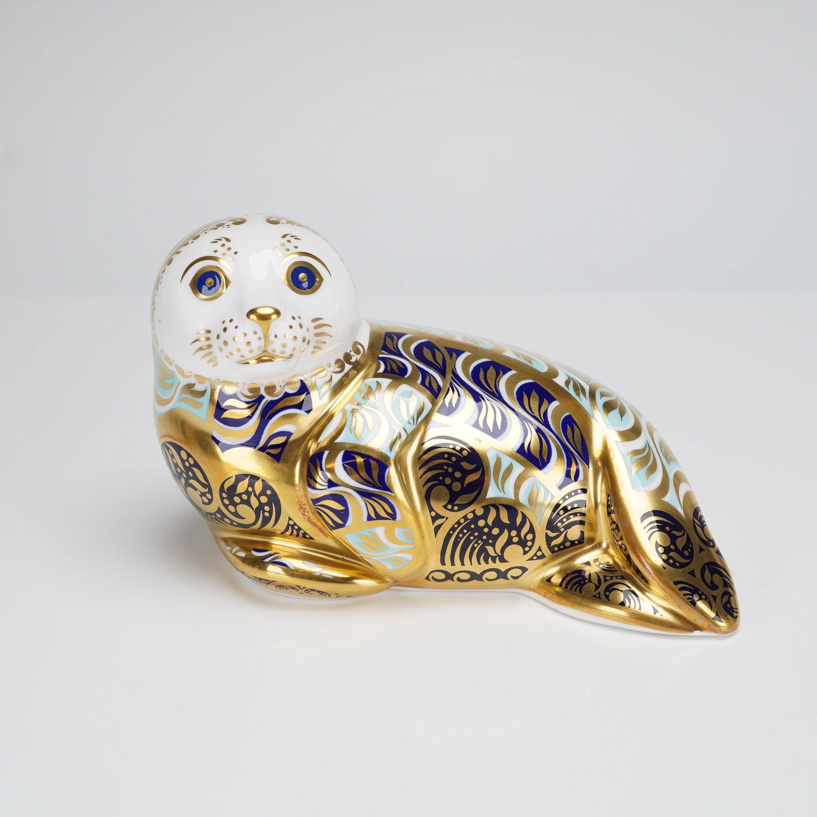 Royal Crown Derby Harbour Seal Paperweight: An English Bone China paperweight figurine by Royal Crown Derby, titled Harbour Seal. The figure is modeled in the form of a reclining seal. The body is decorated in a rich Imari-style palette featuri
