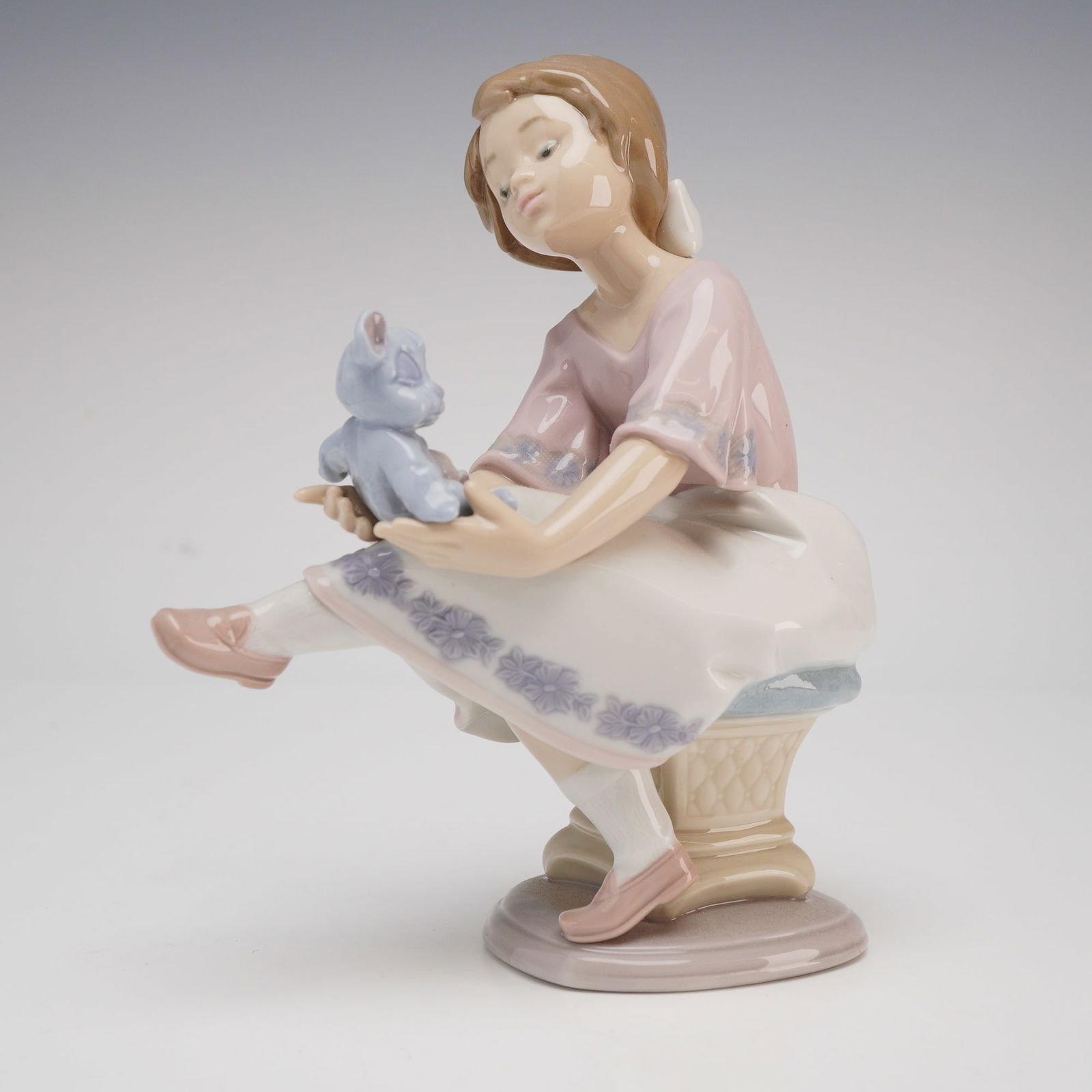 Lladro Porcelain Figurine, Best Friend (Model 7620): A polished glazed Lladro porcelain figurine titled "Best Friend," model number 7620. The piece depicts a seated young girl with her hair tied in a ponytail with a white bow, tenderly cradling a small